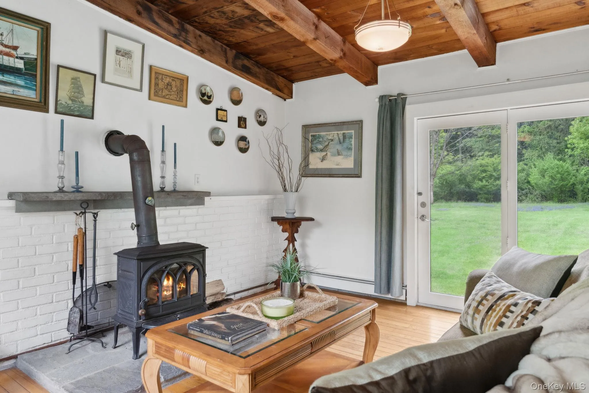 Living room with light wood-style floors, a wood stove, and a wood ceiling with exposed beams Living room with light wood-style floors, a wood stove, and a wood ceiling with exposed beams