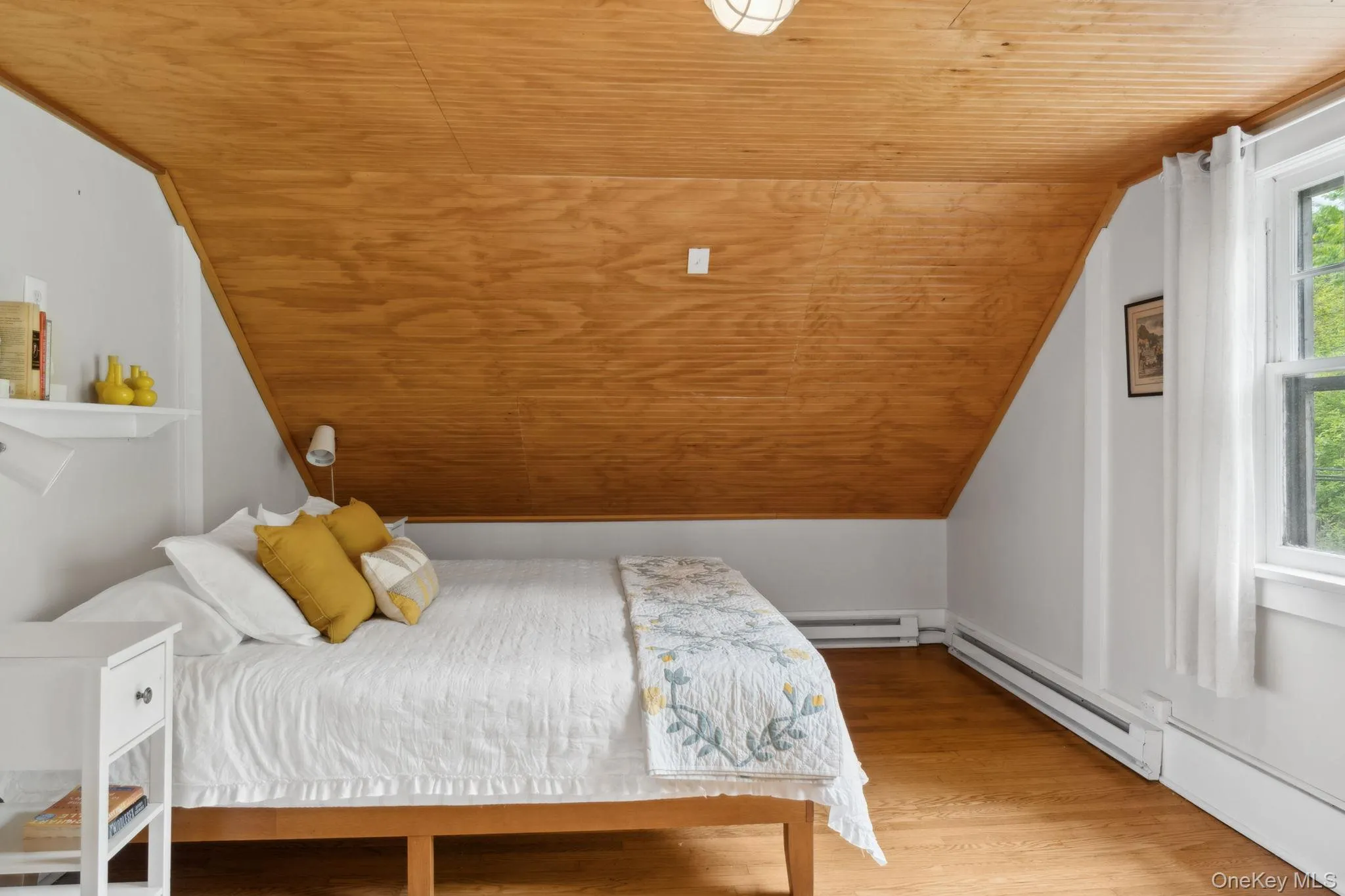 Bedroom with wooden ceiling, light wood finished floors, baseboard heating, and vaulted ceiling Bedroom with wooden ceiling, light wood finished floors, baseboard heating, and vaulted ceiling