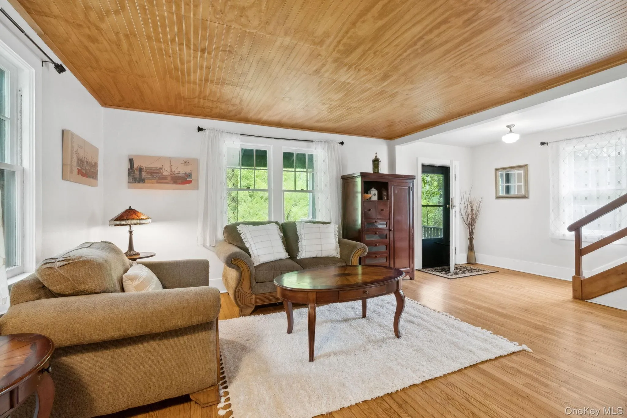 Living room featuring wood finished floors, wooden ceiling, and stairway Living room featuring wood finished floors, wooden ceiling, and stairway