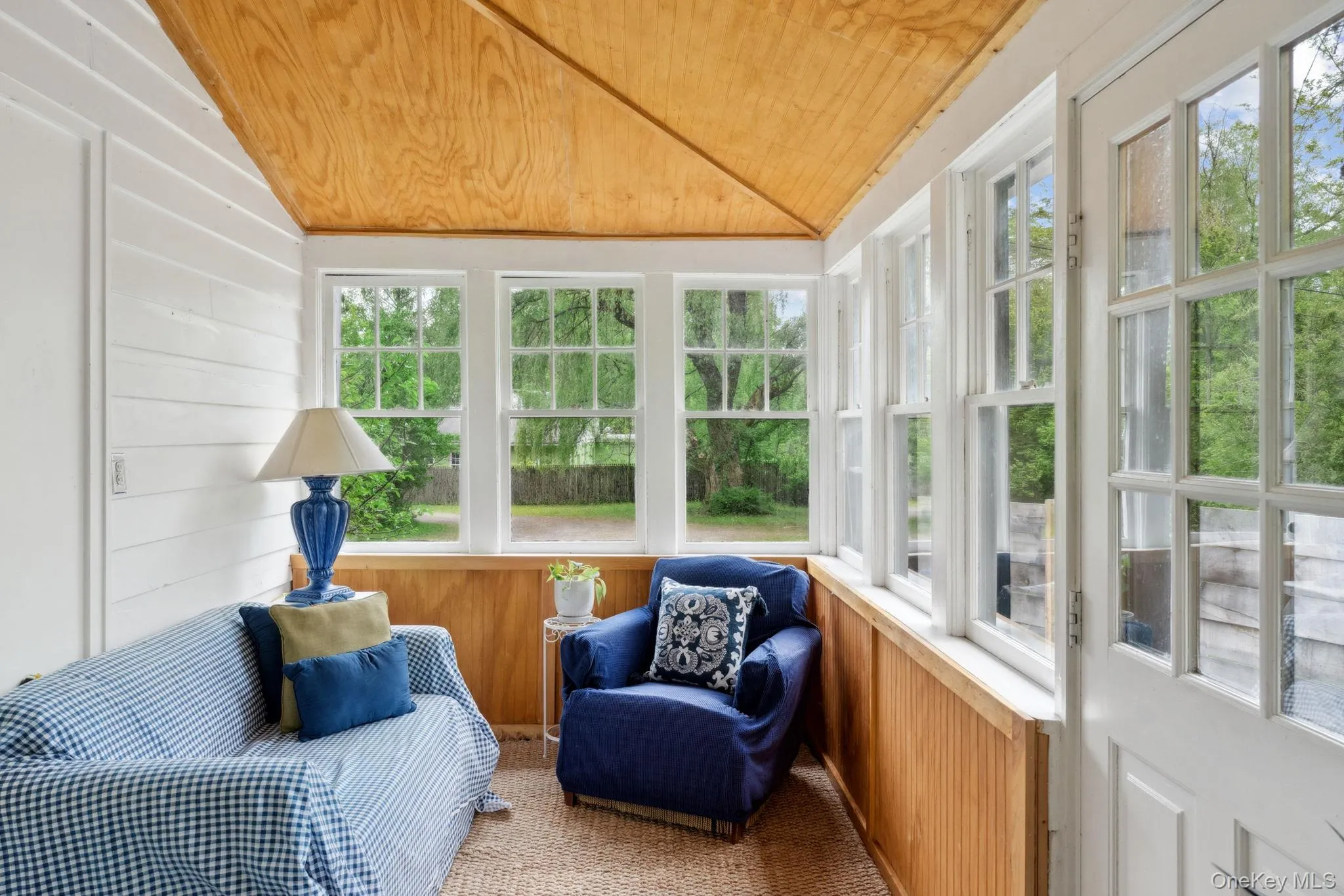 Sunroom featuring wooden walls, vaulted ceiling, wooden ceiling, and carpet flooring Sunroom featuring wooden walls, vaulted ceiling, wooden ceiling, and carpet flooring