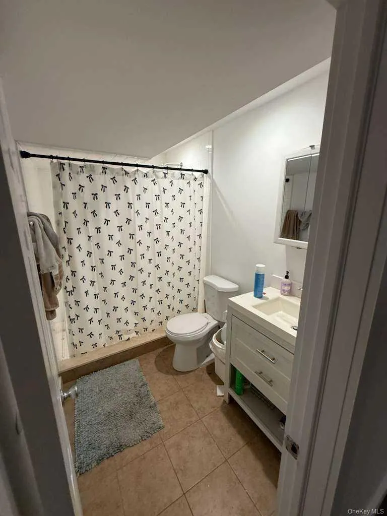 Bathroom with vanity, curtained shower, and light tile patterned floors Bathroom with vanity, curtained shower, and light tile patterned floors