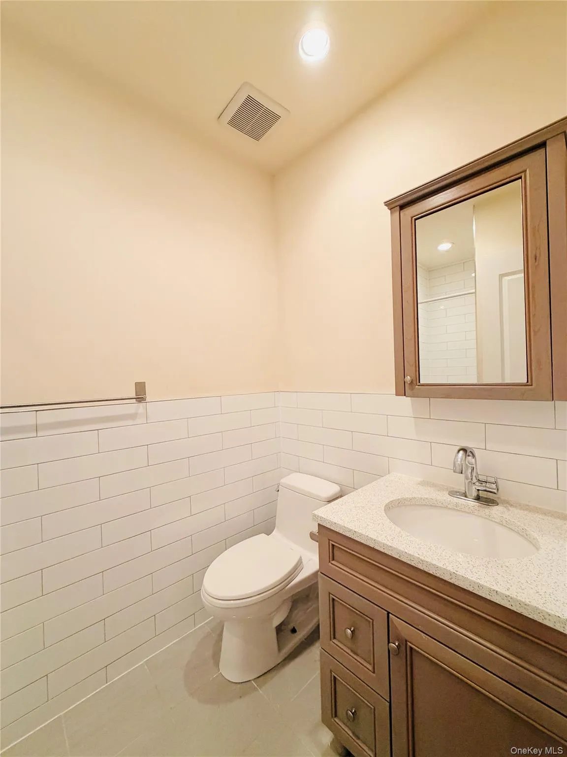 Bathroom with tile walls, vanity, light tile patterned floors, wainscoting, and recessed lighting Bathroom with tile walls, vanity, light tile patterned floors, wainscoting, and recessed lighting