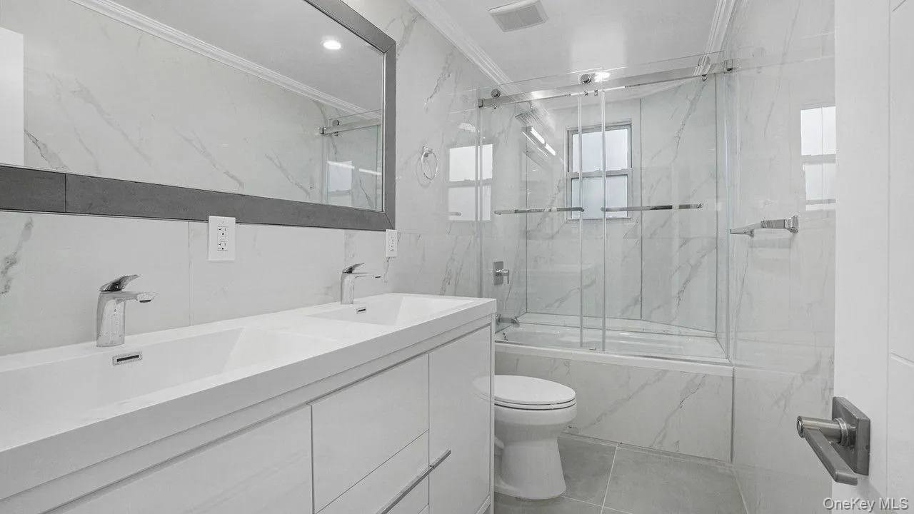 Bathroom with ornamental molding, double vanity, bath / shower combo with glass door, and recessed lighting Bathroom with ornamental molding, double vanity, bath / shower combo with glass door, and recessed lighting