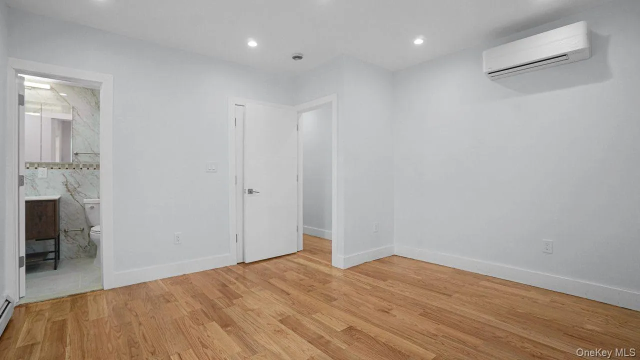 Unfurnished bedroom with light wood-type flooring, a wall mounted AC, recessed lighting, and ensuite bath Unfurnished bedroom with light wood-type flooring, a wall mounted AC, recessed lighting, and ensuite bath
