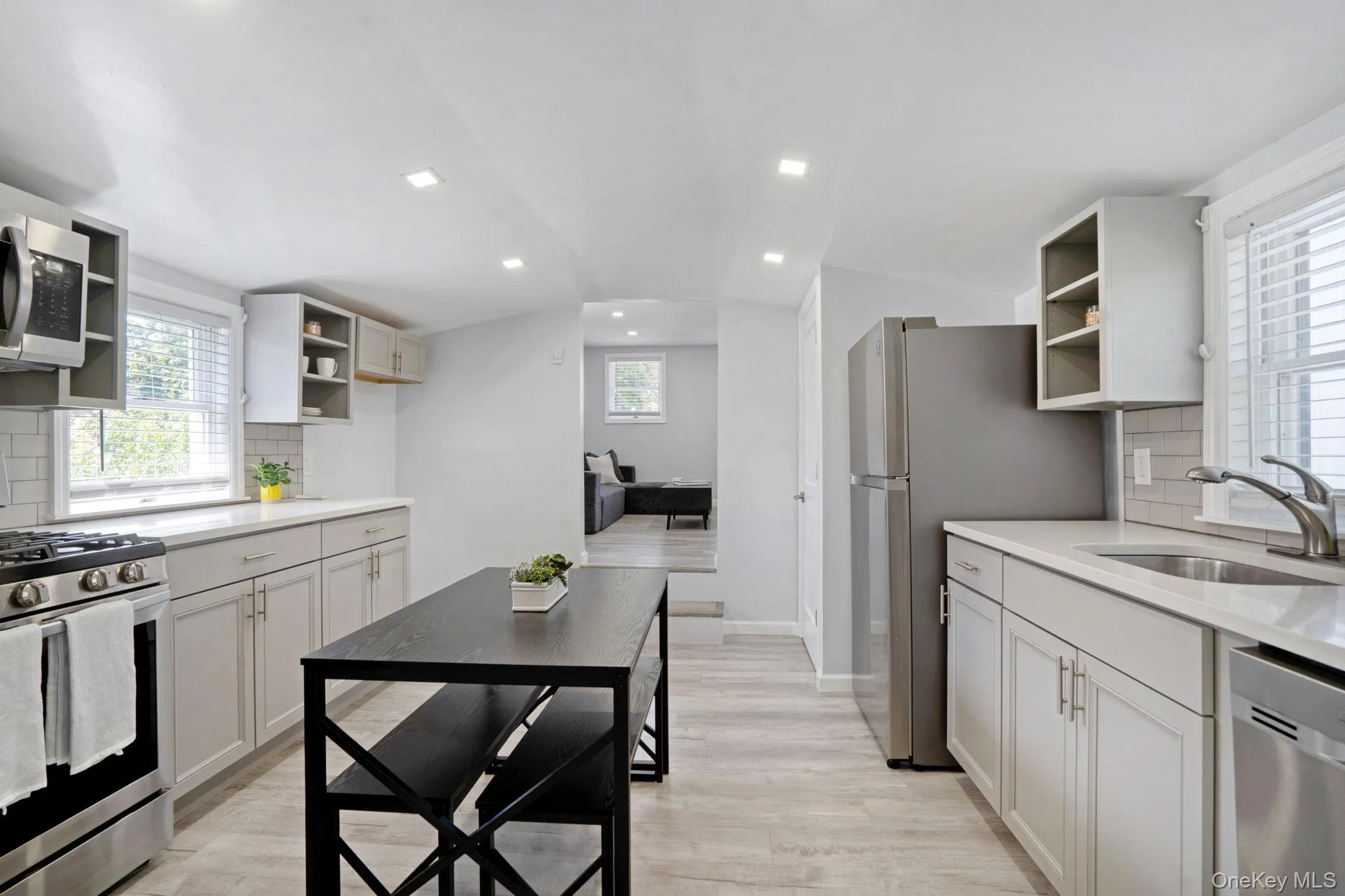 Kitchen featuring open shelves, decorative backsplash, appliances with stainless steel finishes, recessed lighting, and light wood finished floors Kitchen featuring open shelves, decorative backsplash, appliances with stainless steel finishes, recessed lighting, and light wood finished floors