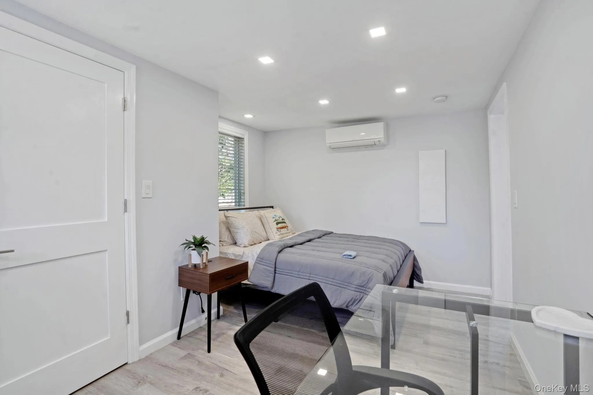 Bedroom featuring light wood-type flooring, recessed lighting, and an AC wall unit Bedroom featuring light wood-type flooring, recessed lighting, and an AC wall unit