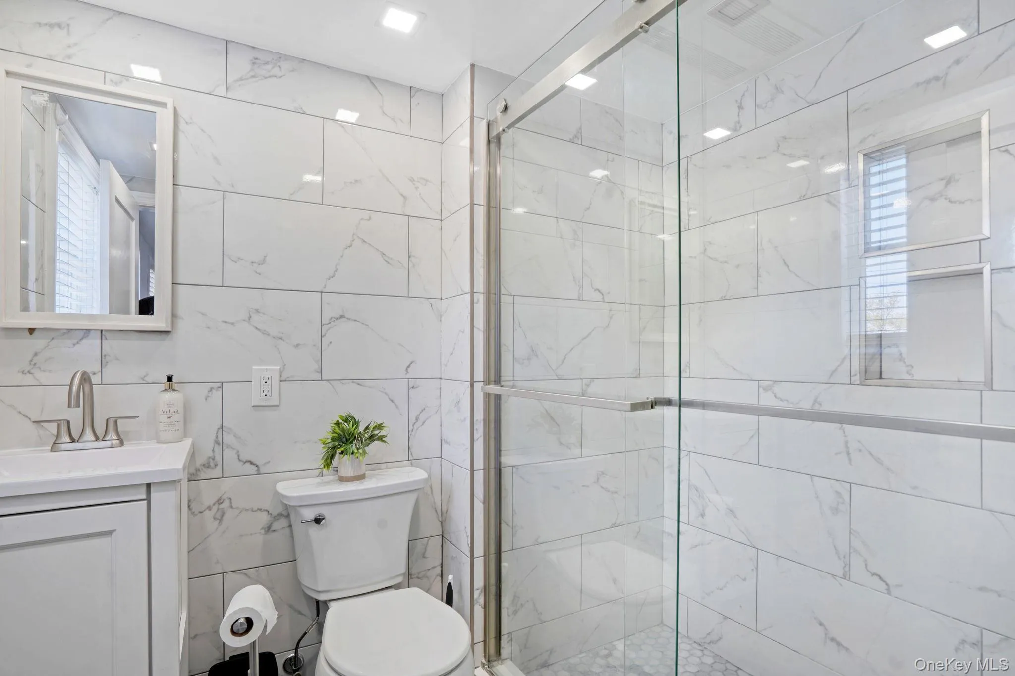 Bathroom with tile walls, a marble finish shower, and vanity Bathroom with tile walls, a marble finish shower, and vanity