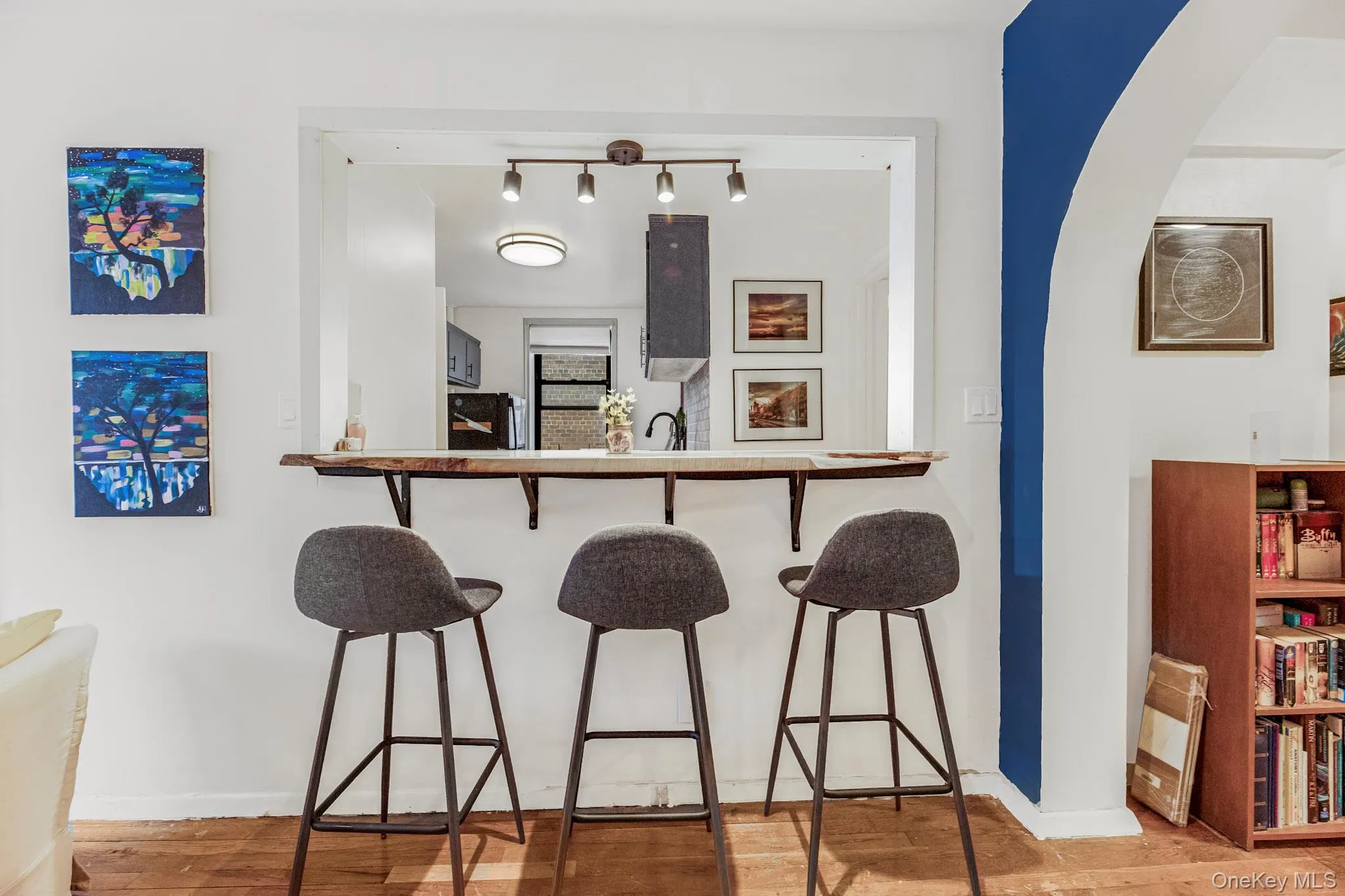 Bar featuring light wood-type flooring, arched walkways, and track lighting Bar featuring light wood-type flooring, arched walkways, and track lighting