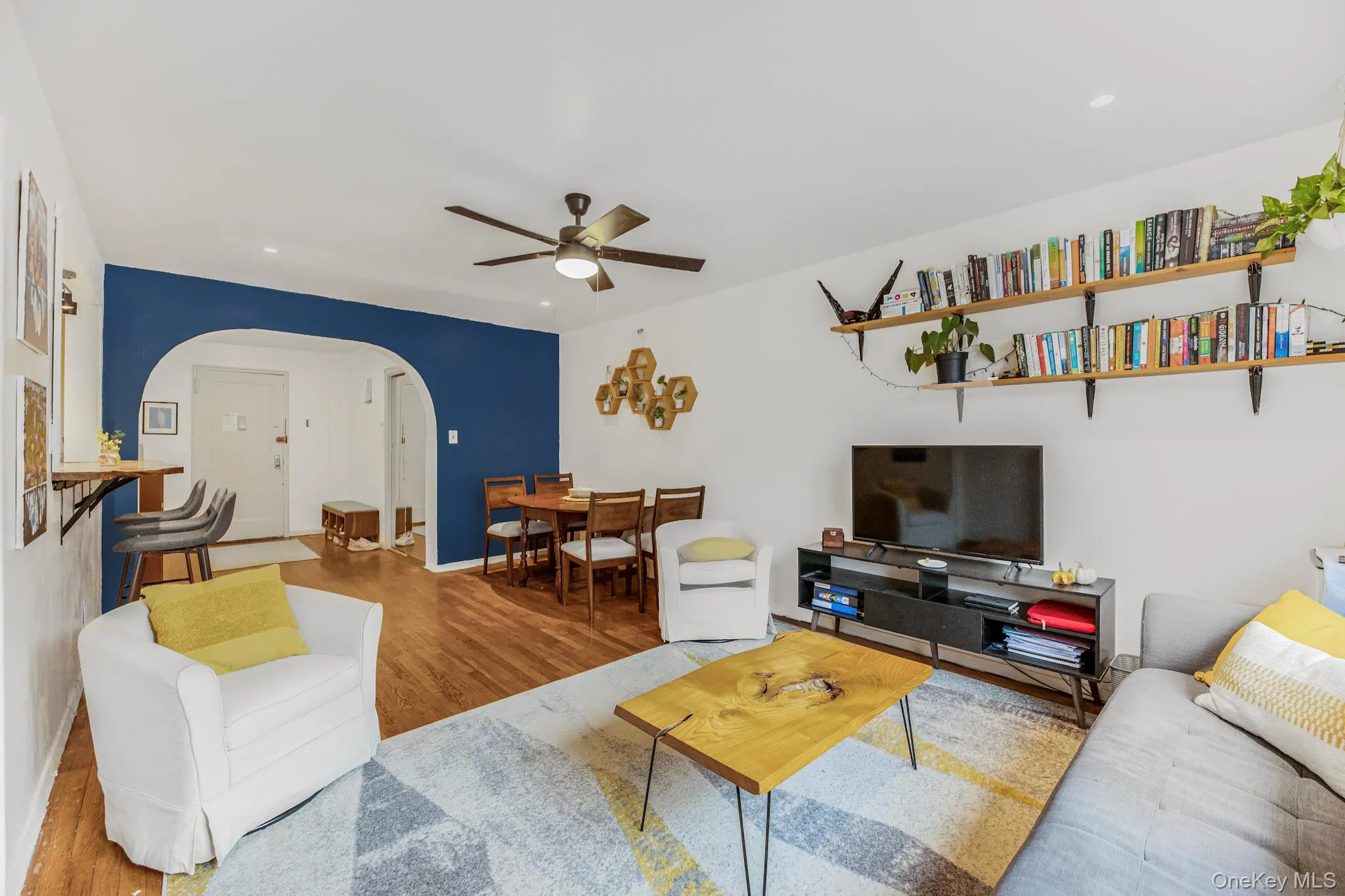 Living area with wood finished floors, a ceiling fan, recessed lighting, and arched walkways Living area with wood finished floors, a ceiling fan, recessed lighting, and arched walkways