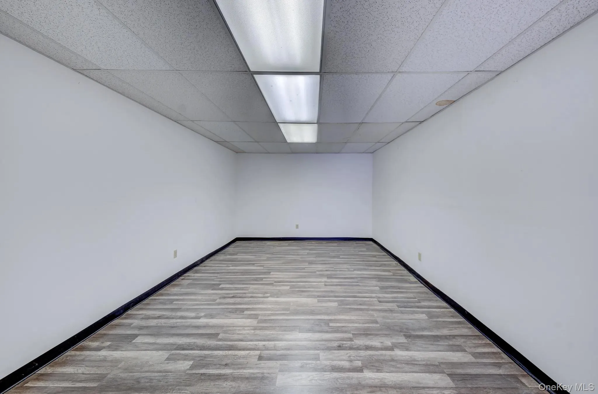 Empty room with a drop ceiling and wood finished floors Empty room with a drop ceiling and wood finished floors