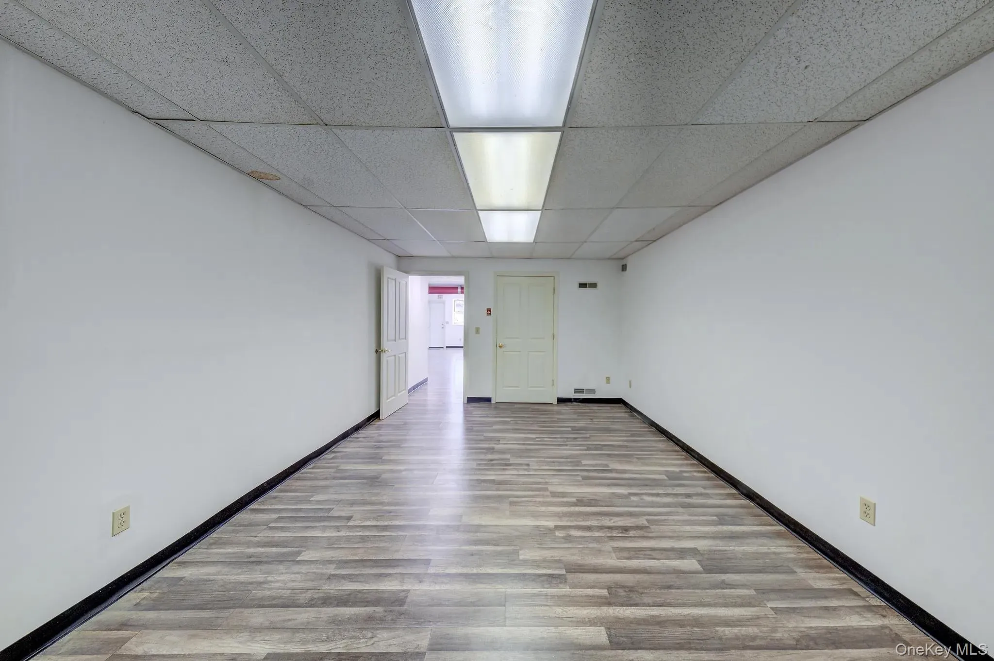 Unfurnished room featuring a paneled ceiling and wood finished floors Unfurnished room featuring a paneled ceiling and wood finished floors