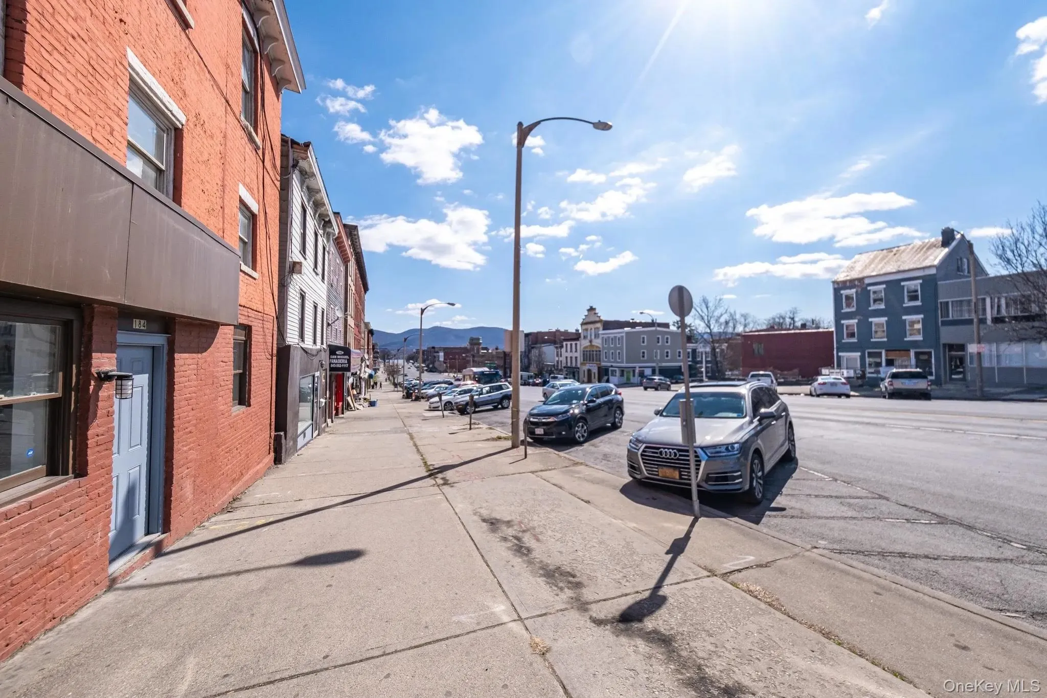 View of asphalt road featuring sidewalks, a mountain view, curbs, and traffic signs View of asphalt road featuring sidewalks, a mountain view, curbs, and traffic signs