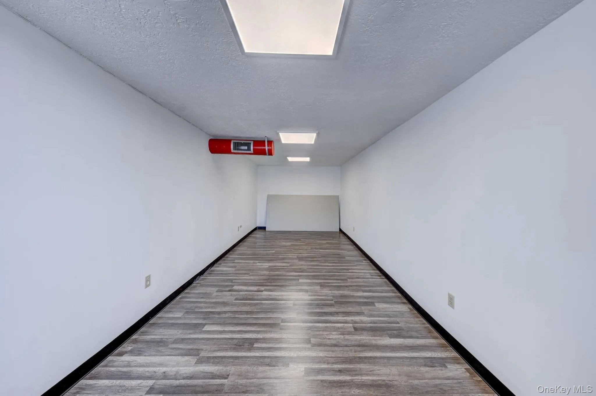 Empty room with a textured ceiling and wood finished floors Empty room with a textured ceiling and wood finished floors