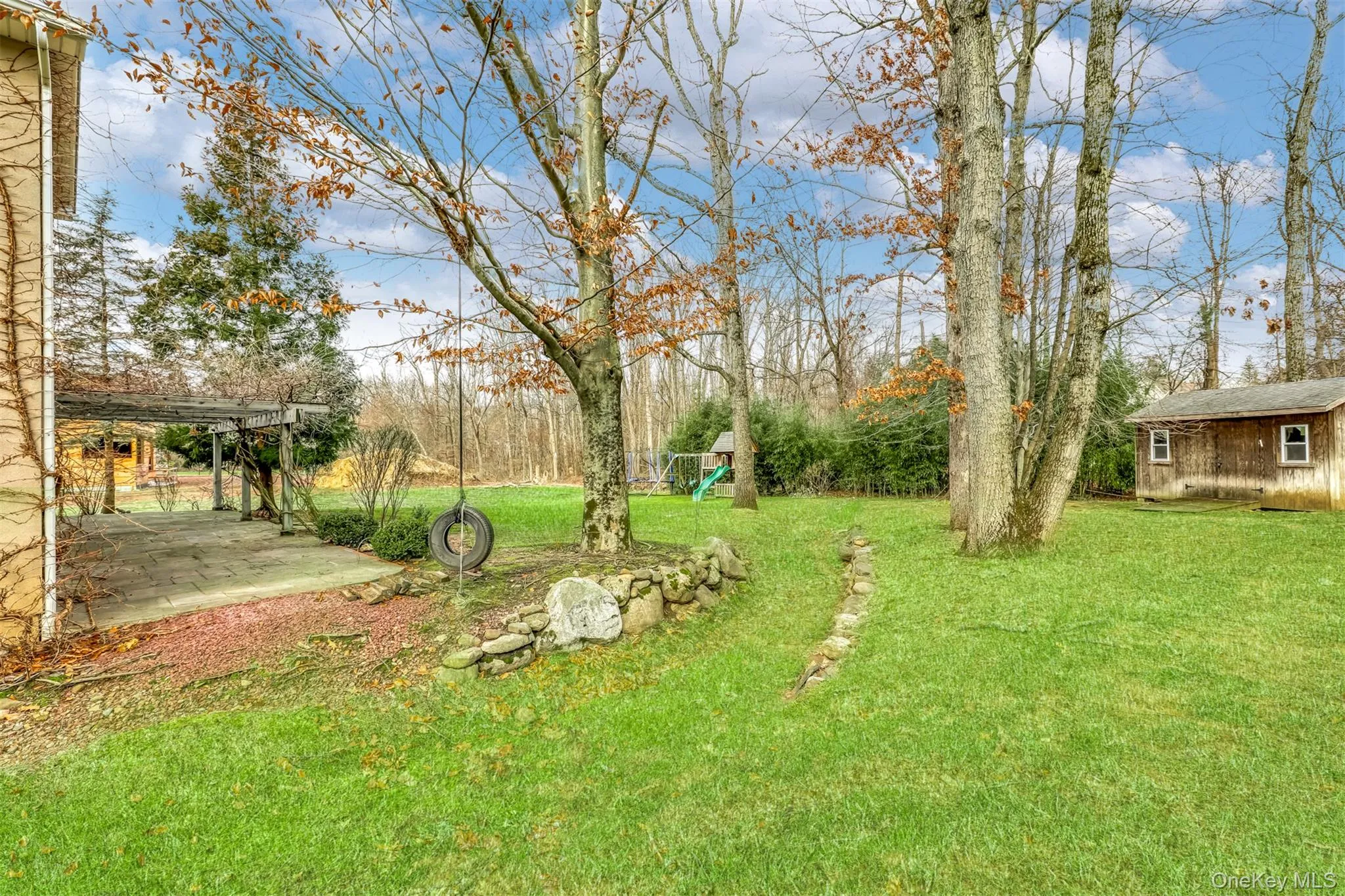 View of green lawn featuring an outbuilding, a playground, and a patio area View of green lawn featuring an outbuilding, a playground, and a patio area