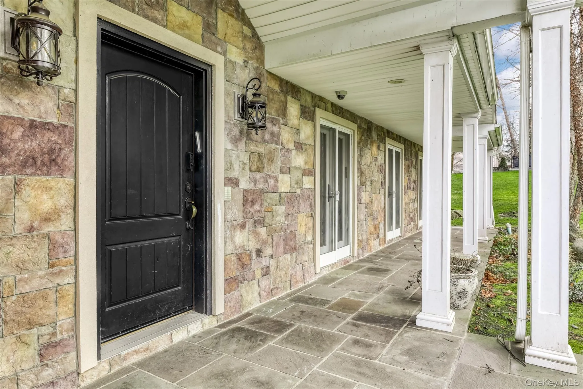 Property entrance featuring stone siding and a porch Property entrance featuring stone siding and a porch