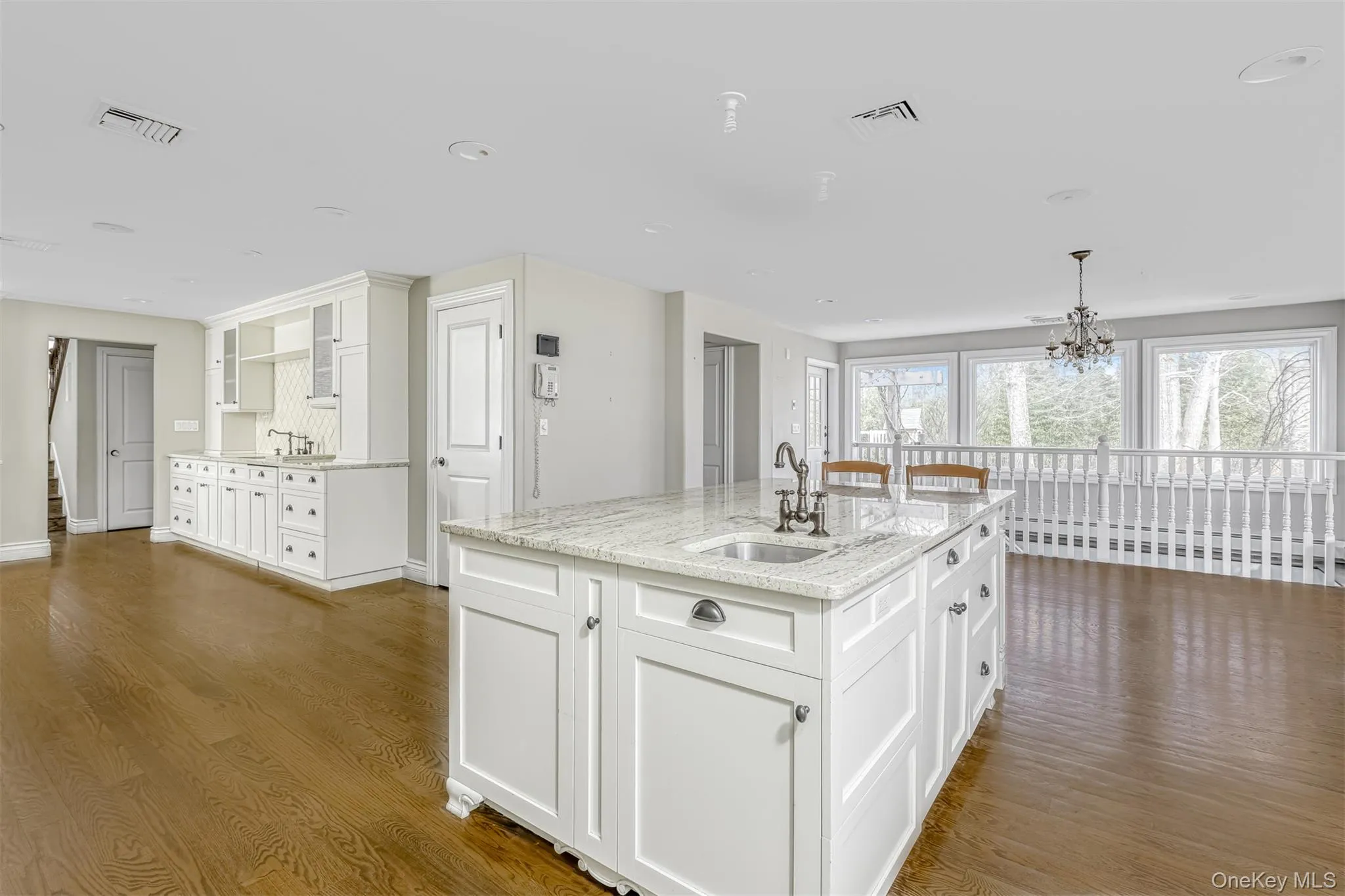 Kitchen featuring white cabinetry, light stone counters, dark wood-type flooring, hanging light fixtures, and recessed lighting Kitchen featuring white cabinetry, light stone counters, dark wood-type flooring, hanging light fixtures, and recessed lighting