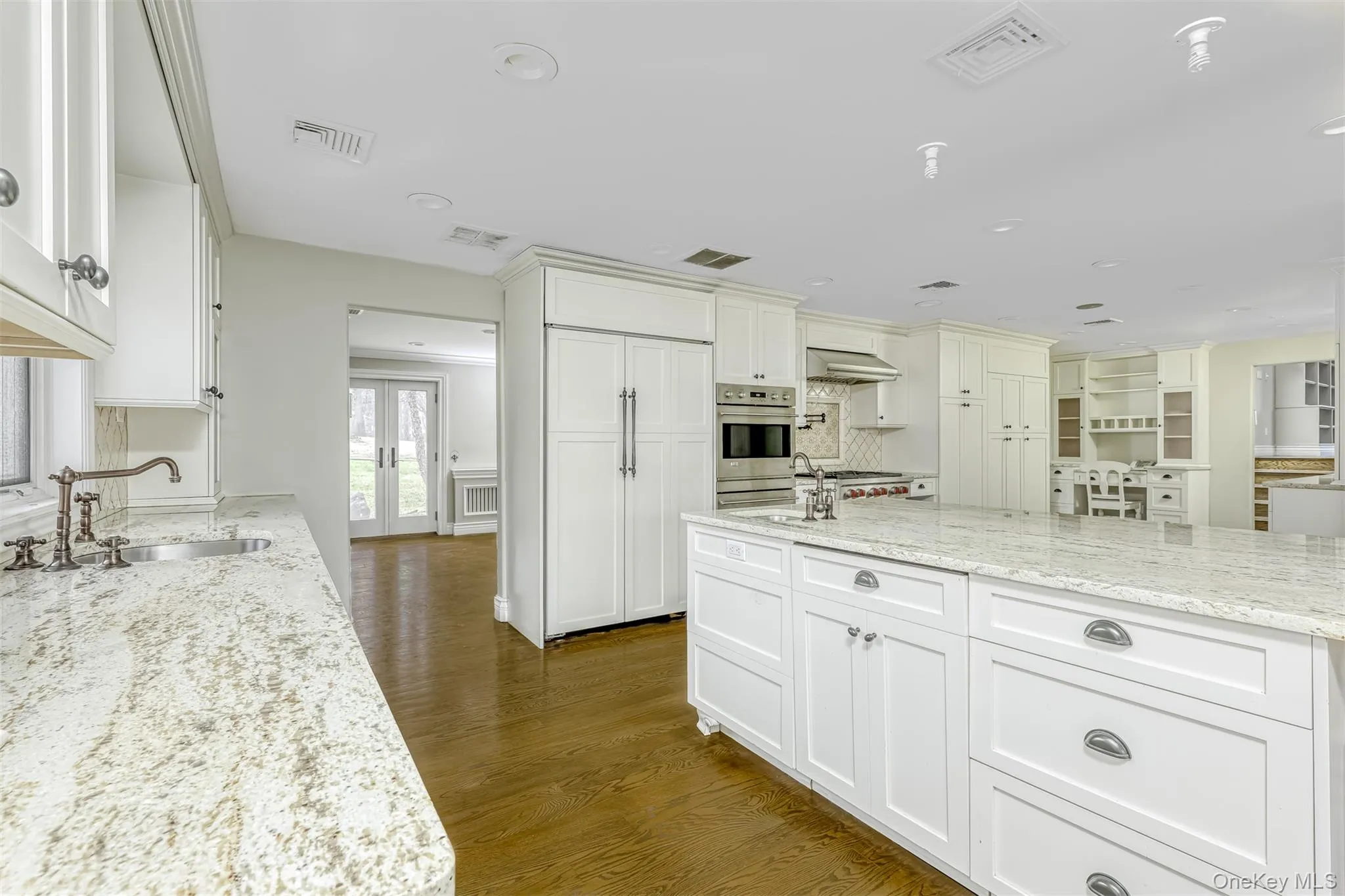 Kitchen with light stone counters, dark wood finished floors, oven, french doors, and white cabinets Kitchen with light stone counters, dark wood finished floors, oven, french doors, and white cabinets