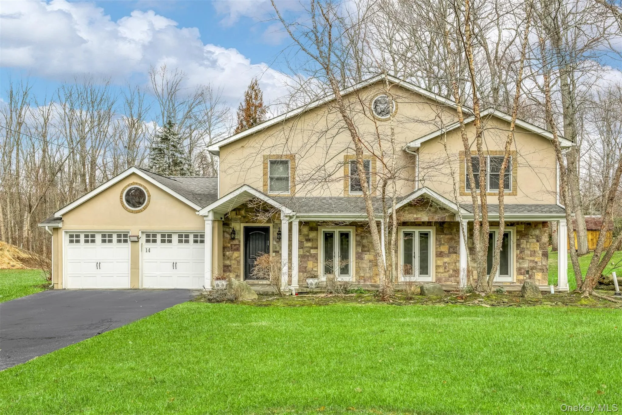 Traditional-style home with stone siding, a front yard, and stucco siding Traditional-style home with stone siding, a front yard, and stucco siding