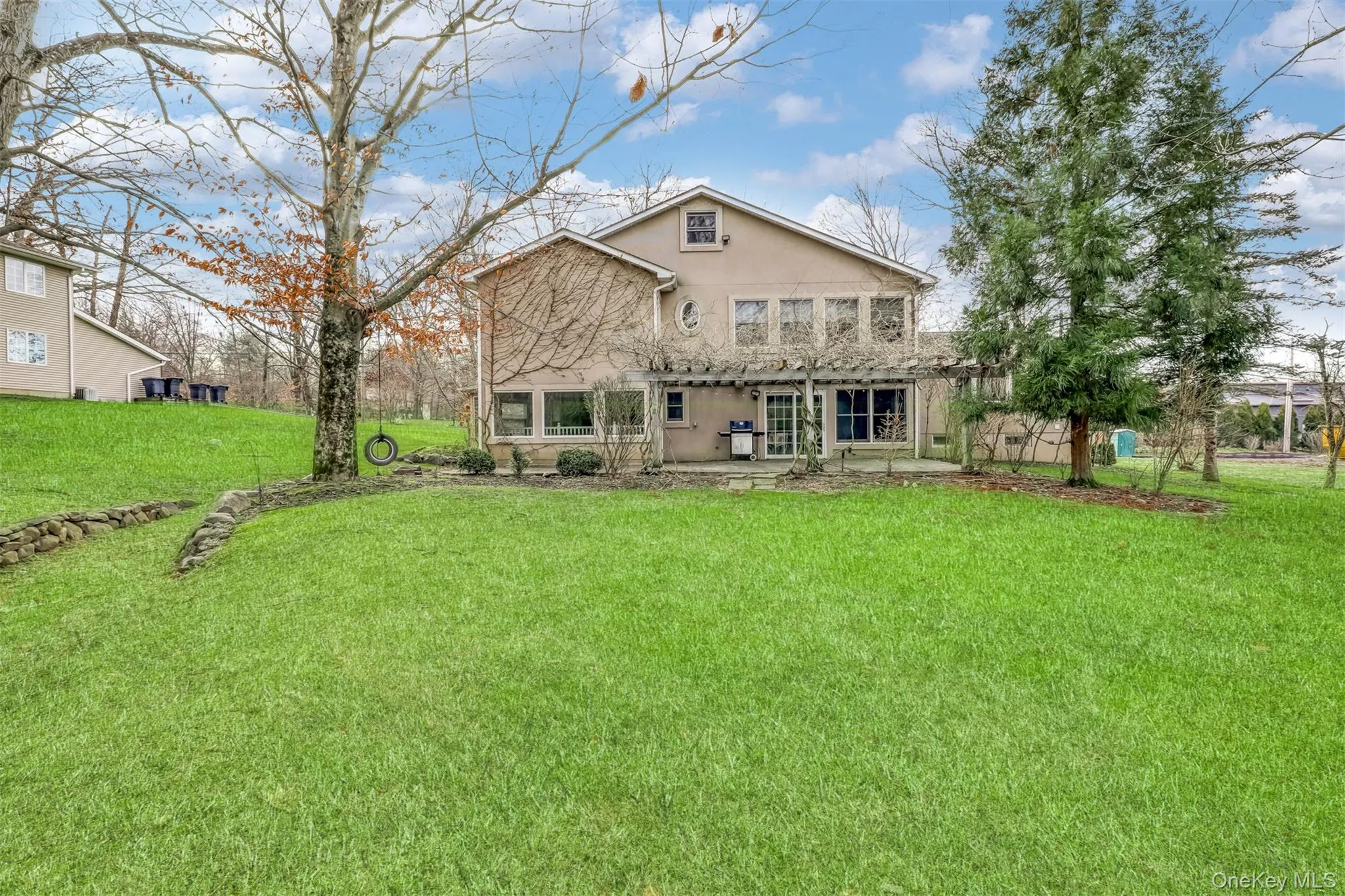 Back of house with a patio, a lawn, and stucco siding Back of house with a patio, a lawn, and stucco siding
