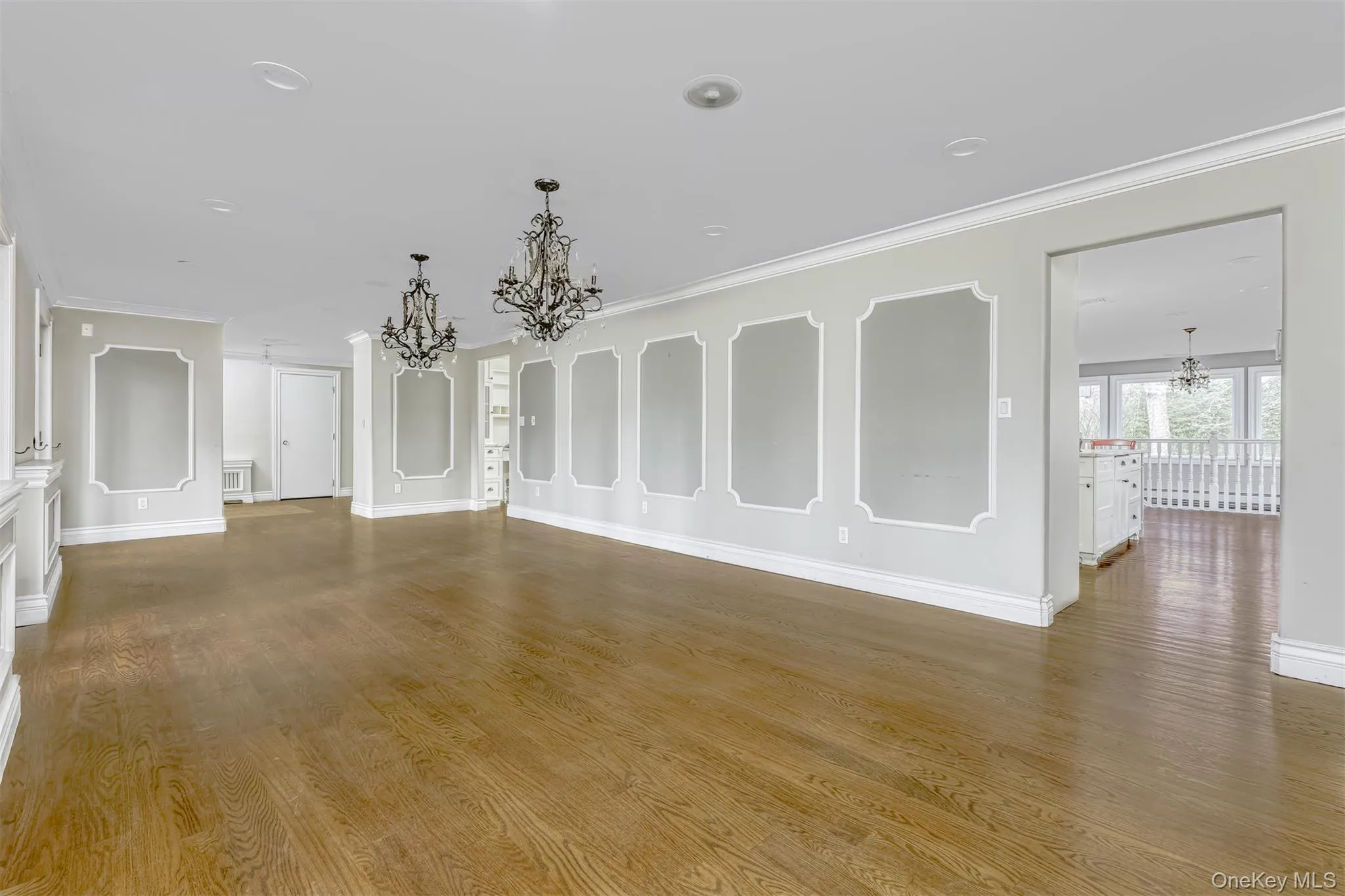 Unfurnished living room with a chandelier, crown molding, and dark wood-style flooring Unfurnished living room with a chandelier, crown molding, and dark wood-style flooring