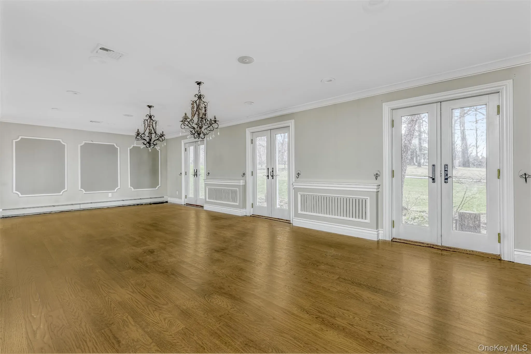 Unfurnished dining area featuring french doors, crown molding, plenty of natural light, a baseboard radiator, and a decorative wall Unfurnished dining area featuring french doors, crown molding, plenty of natural light, a baseboard radiator, and a decorative wall