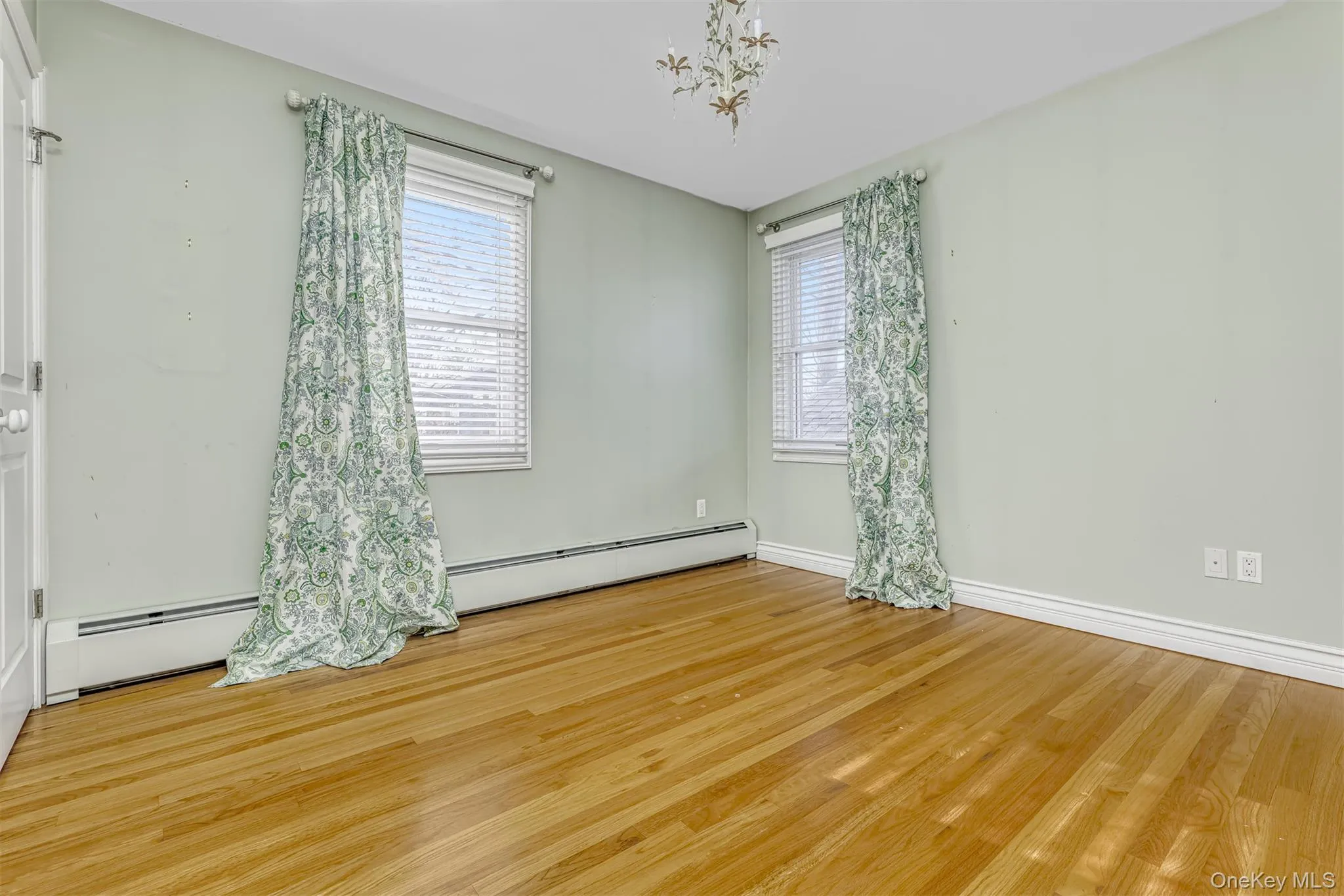 Empty room with wood finished floors and a baseboard radiator Empty room with wood finished floors and a baseboard radiator