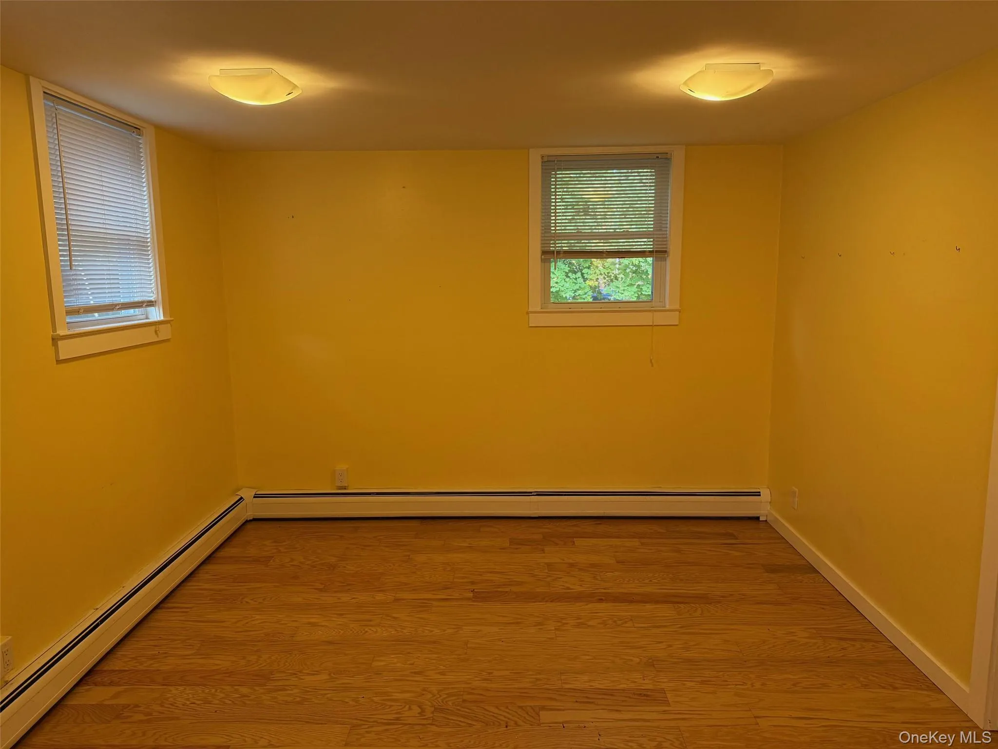 Spare room featuring baseboard heating and wood finished floors Spare room featuring baseboard heating and wood finished floors