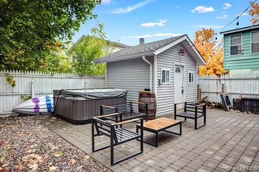 Fenced backyard with a patio, an outdoor structure, and a hot tub Fenced backyard with a patio, an outdoor structure, and a hot tub