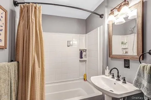 Bathroom featuring shower / bath combo with shower curtain and a sink Bathroom featuring shower / bath combo with shower curtain and a sink