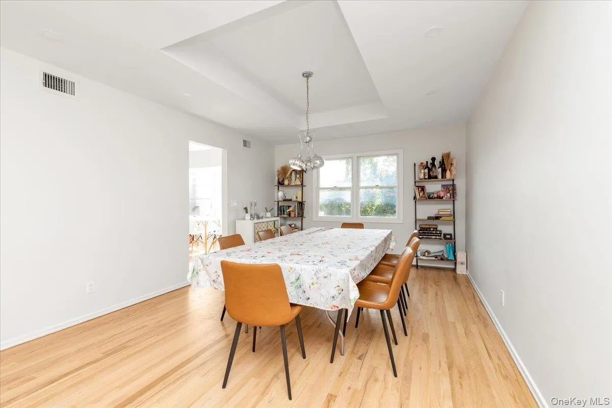Dining area featuring a tray ceiling, light wood finished floors, and a chandelier Dining area featuring a tray ceiling, light wood finished floors, and a chandelier