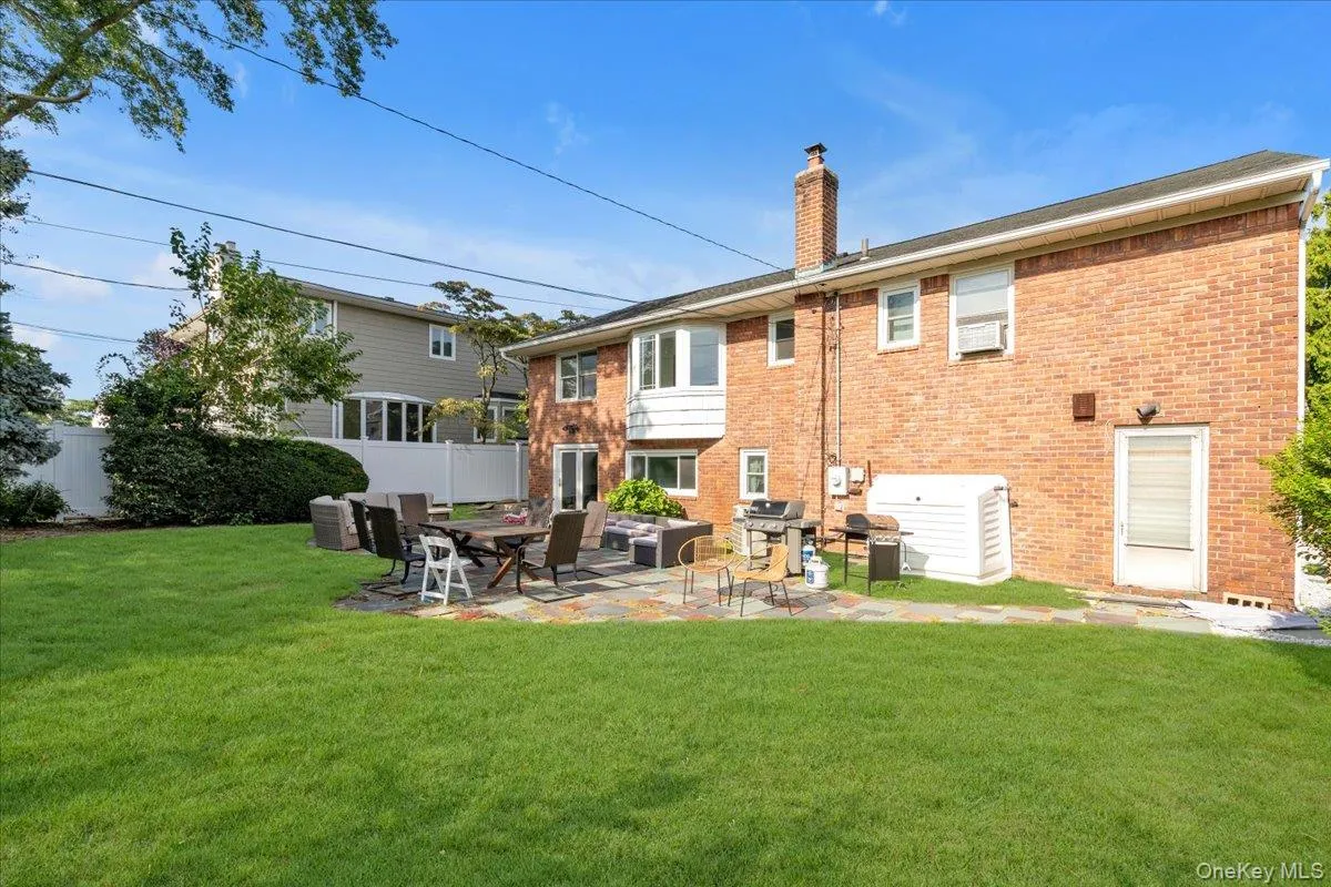 Rear view of house with a chimney, a patio, and brick siding Rear view of house with a chimney, a patio, and brick siding