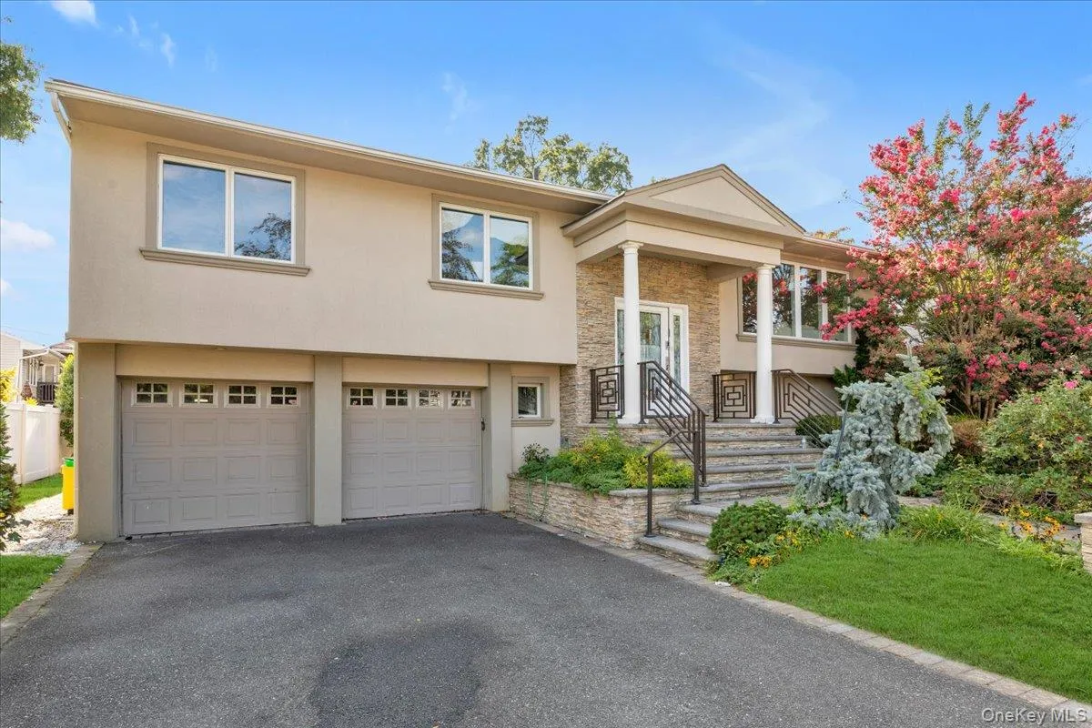 Split foyer home featuring stucco siding, stone siding, an attached garage, and driveway Split foyer home featuring stucco siding, stone siding, an attached garage, and driveway