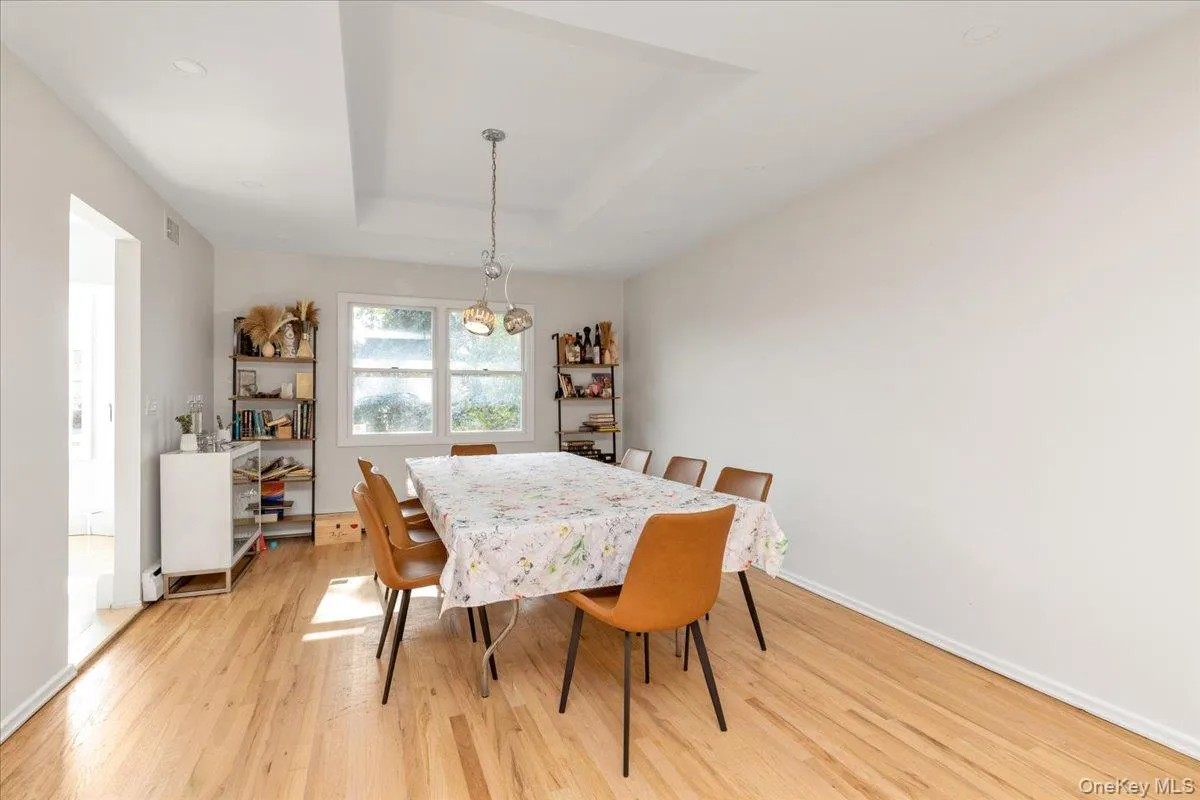 Dining space with a tray ceiling and light wood-style floors Dining space with a tray ceiling and light wood-style floors