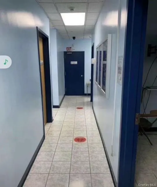 Corridor featuring a paneled ceiling and light tile patterned flooring Corridor featuring a paneled ceiling and light tile patterned flooring