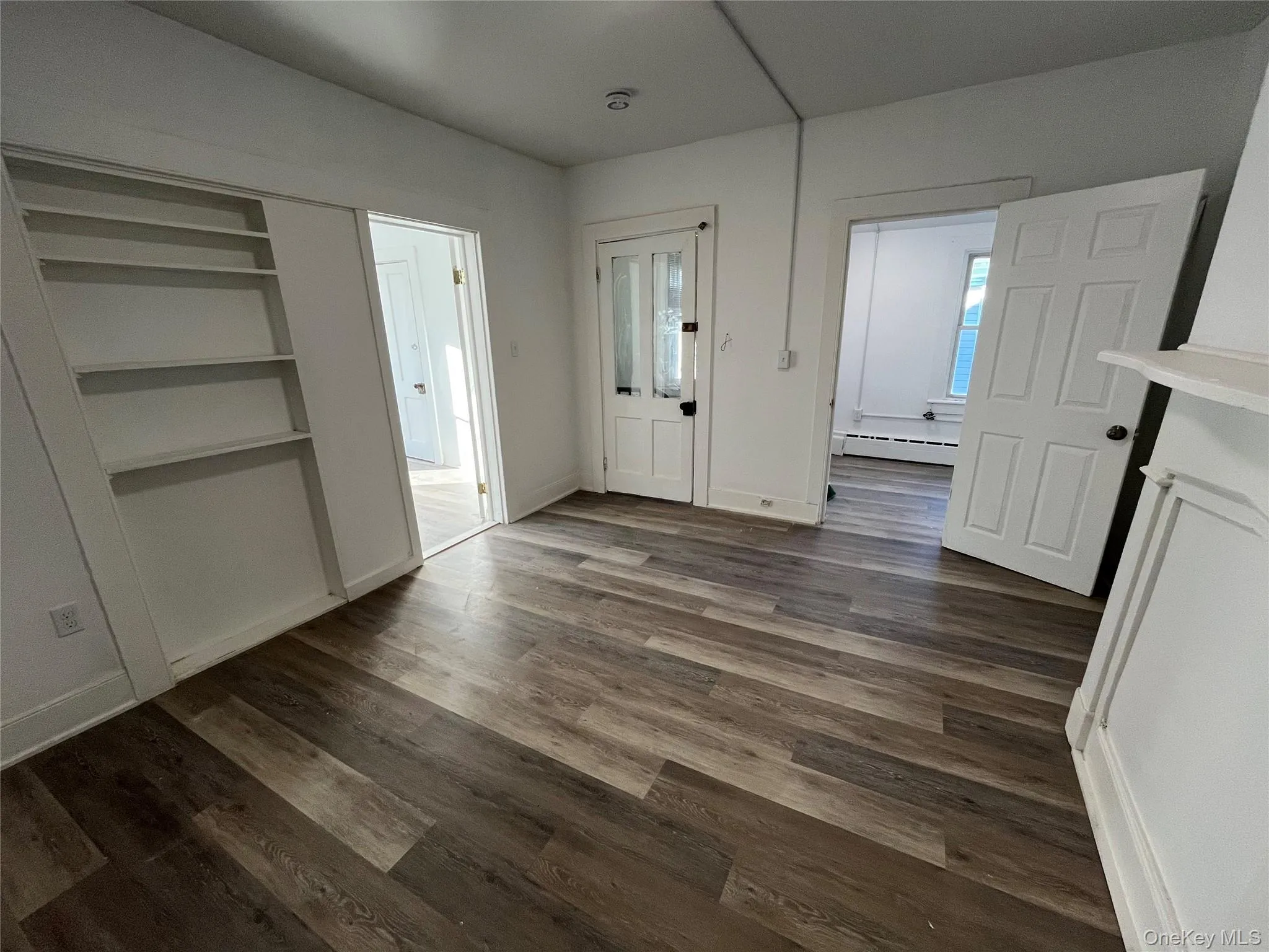 Foyer entrance featuring dark wood-type flooring and a baseboard radiator Foyer entrance featuring dark wood-type flooring and a baseboard radiator