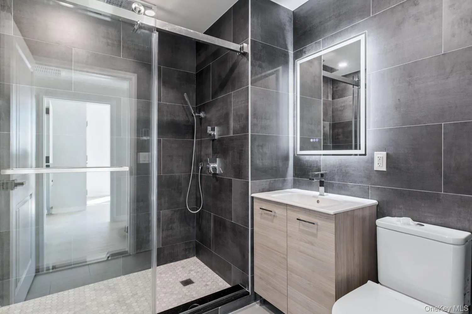 Bathroom with a shower stall, vanity, and tile walls Bathroom with a shower stall, vanity, and tile walls