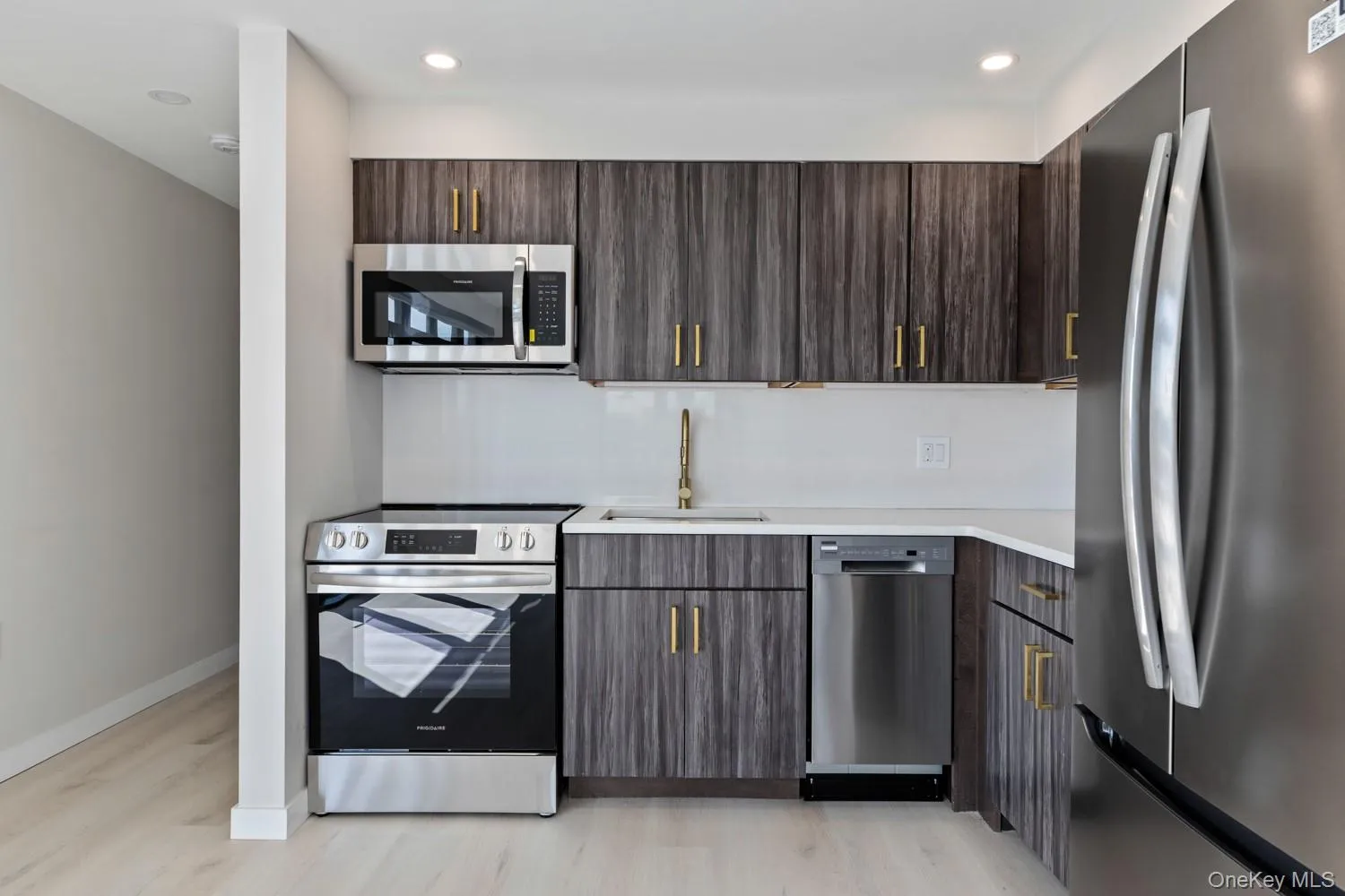 Kitchen with appliances with stainless steel finishes, dark brown cabinets, modern cabinets, light wood-style floors, and recessed lighting Kitchen with appliances with stainless steel finishes, dark brown cabinets, modern cabinets, light wood-style floors, and recessed lighting