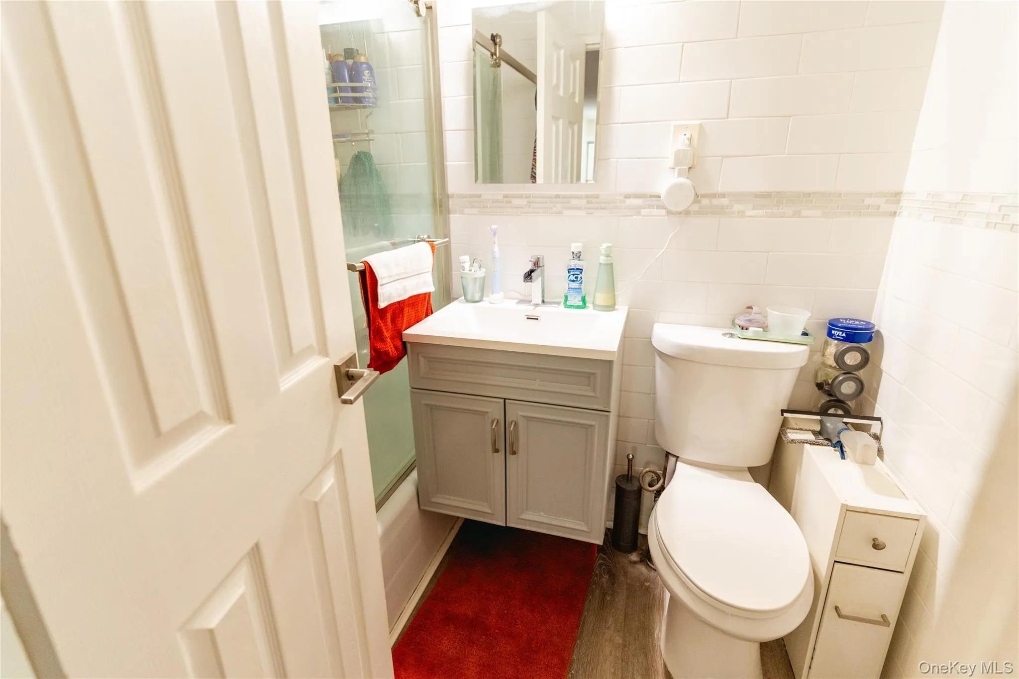 Bathroom with vanity, tile walls, and enclosed tub / shower combo Bathroom with vanity, tile walls, and enclosed tub / shower combo