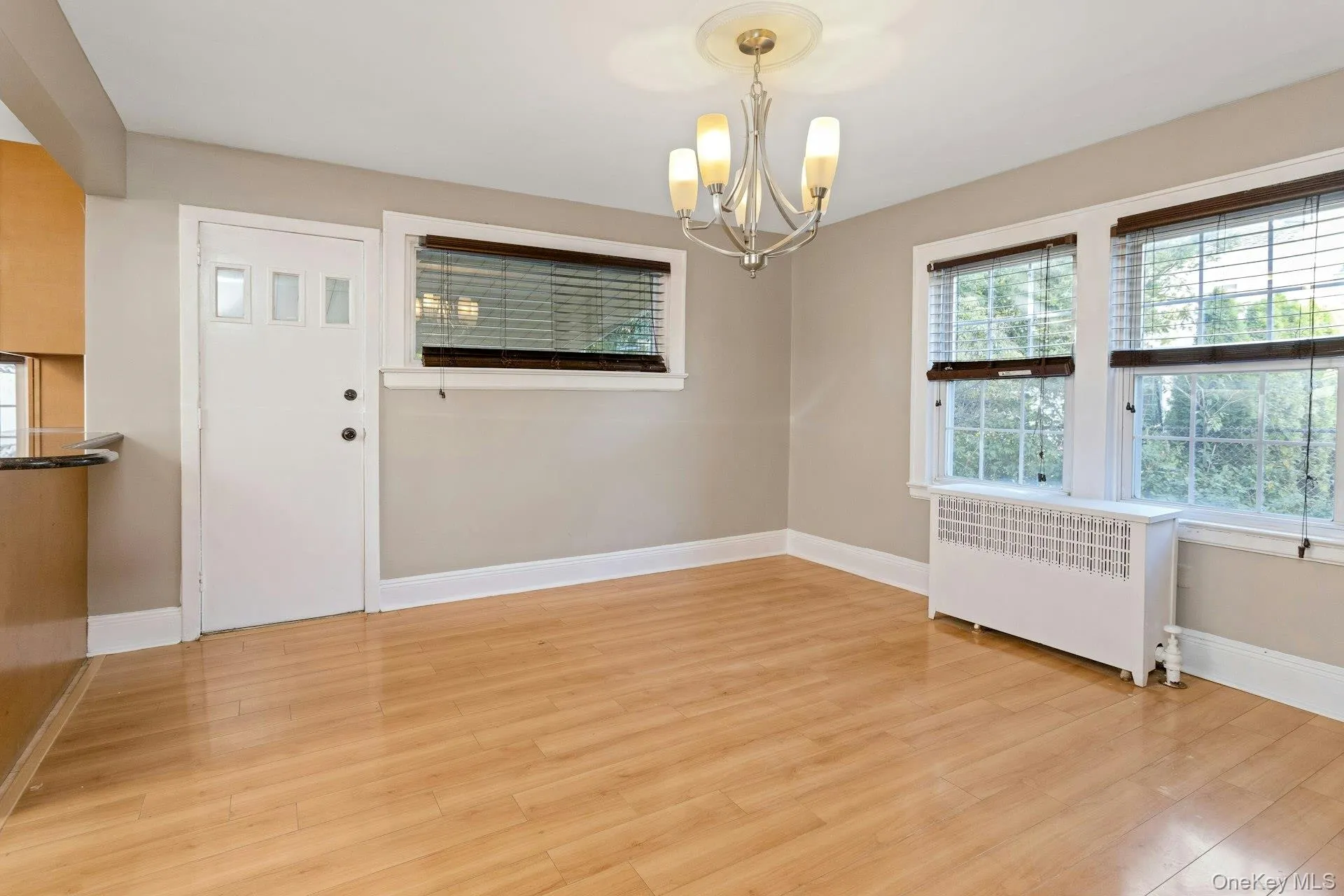Unfurnished dining area with radiator heating unit, light wood-style floors, and a chandelier Unfurnished dining area with radiator heating unit, light wood-style floors, and a chandelier
