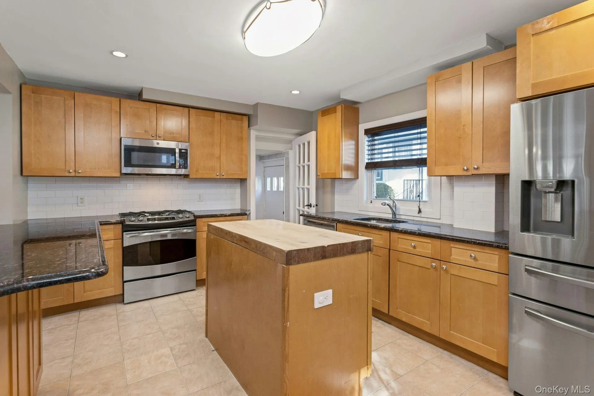 Kitchen with decorative backsplash, appliances with stainless steel finishes, dark stone countertops, and recessed lighting Kitchen with decorative backsplash, appliances with stainless steel finishes, dark stone countertops, and recessed lighting