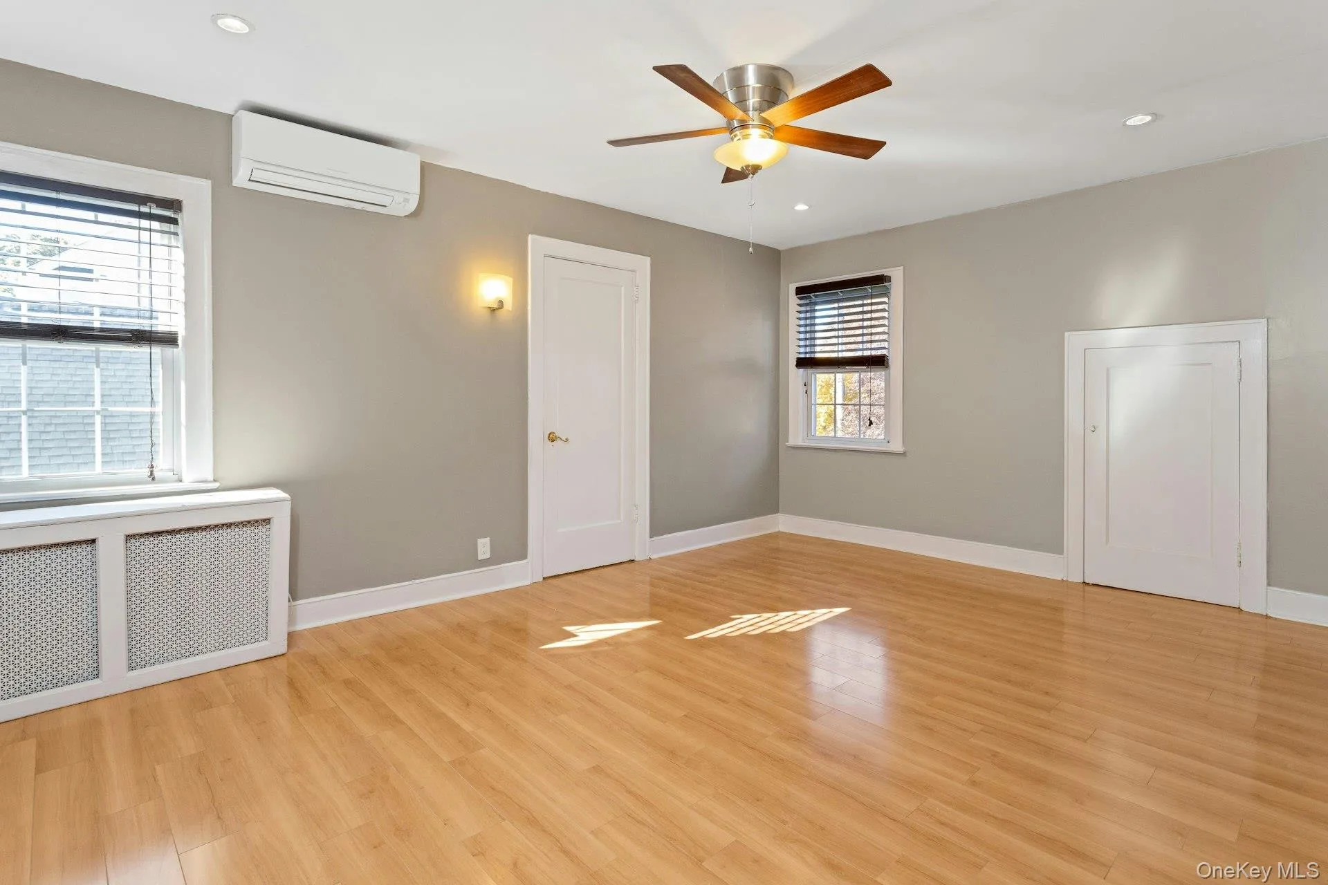 Empty room with radiator, recessed lighting, light wood-type flooring, a wall unit AC, and ceiling fan Empty room with radiator, recessed lighting, light wood-type flooring, a wall unit AC, and ceiling fan