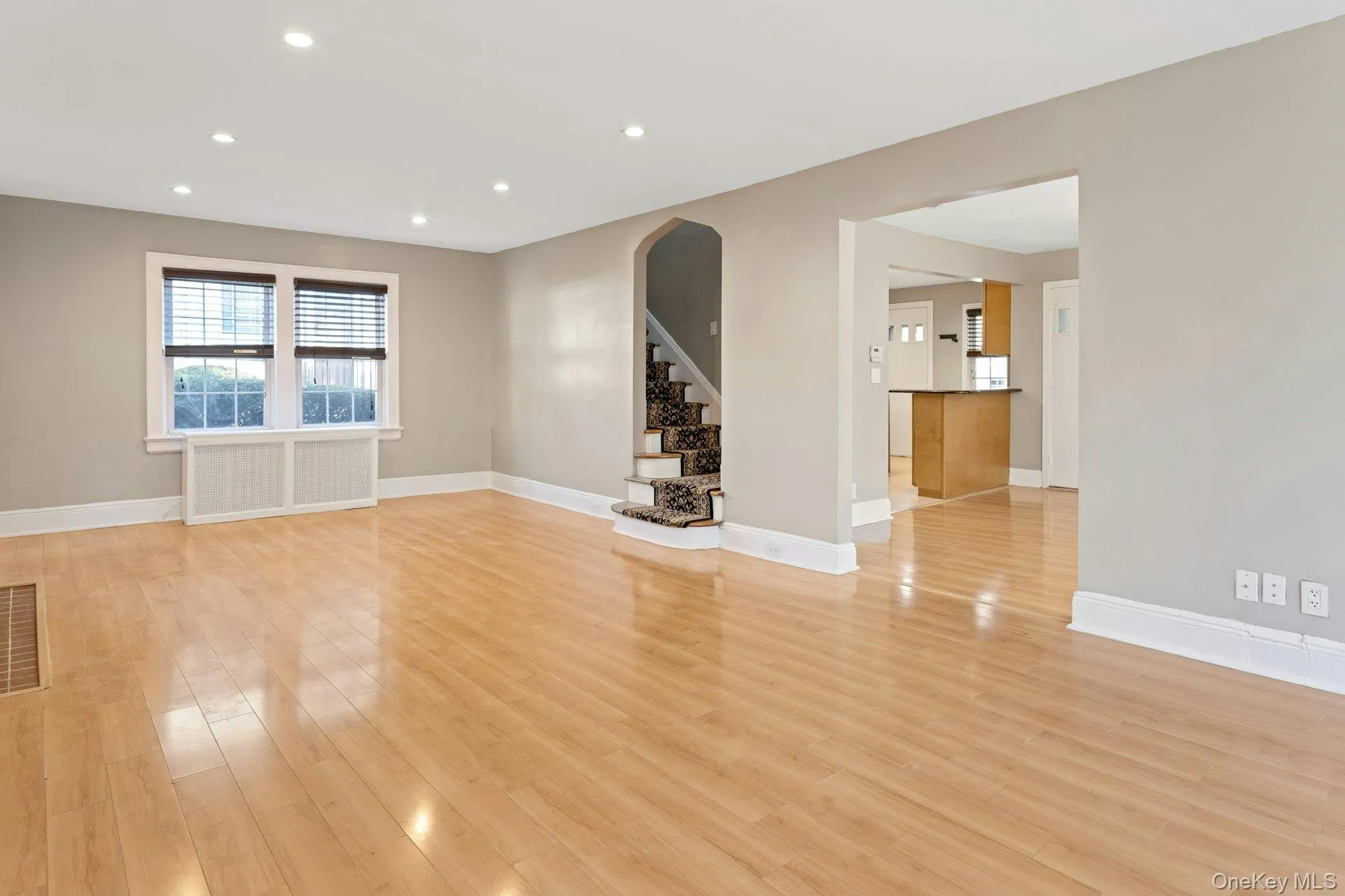 Unfurnished room featuring stairs, arched walkways, recessed lighting, and light wood-style flooring Unfurnished room featuring stairs, arched walkways, recessed lighting, and light wood-style flooring