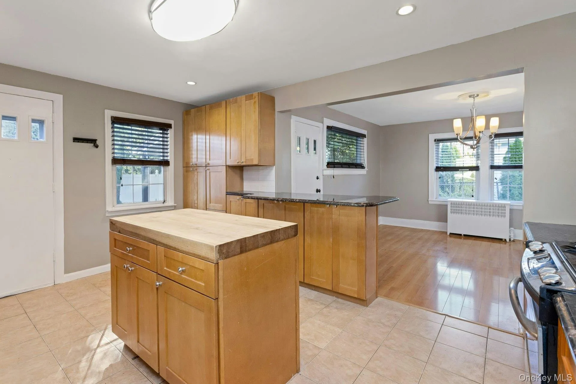 Kitchen with stainless steel stove, butcher block countertops, radiator, recessed lighting, and a kitchen island Kitchen with stainless steel stove, butcher block countertops, radiator, recessed lighting, and a kitchen island