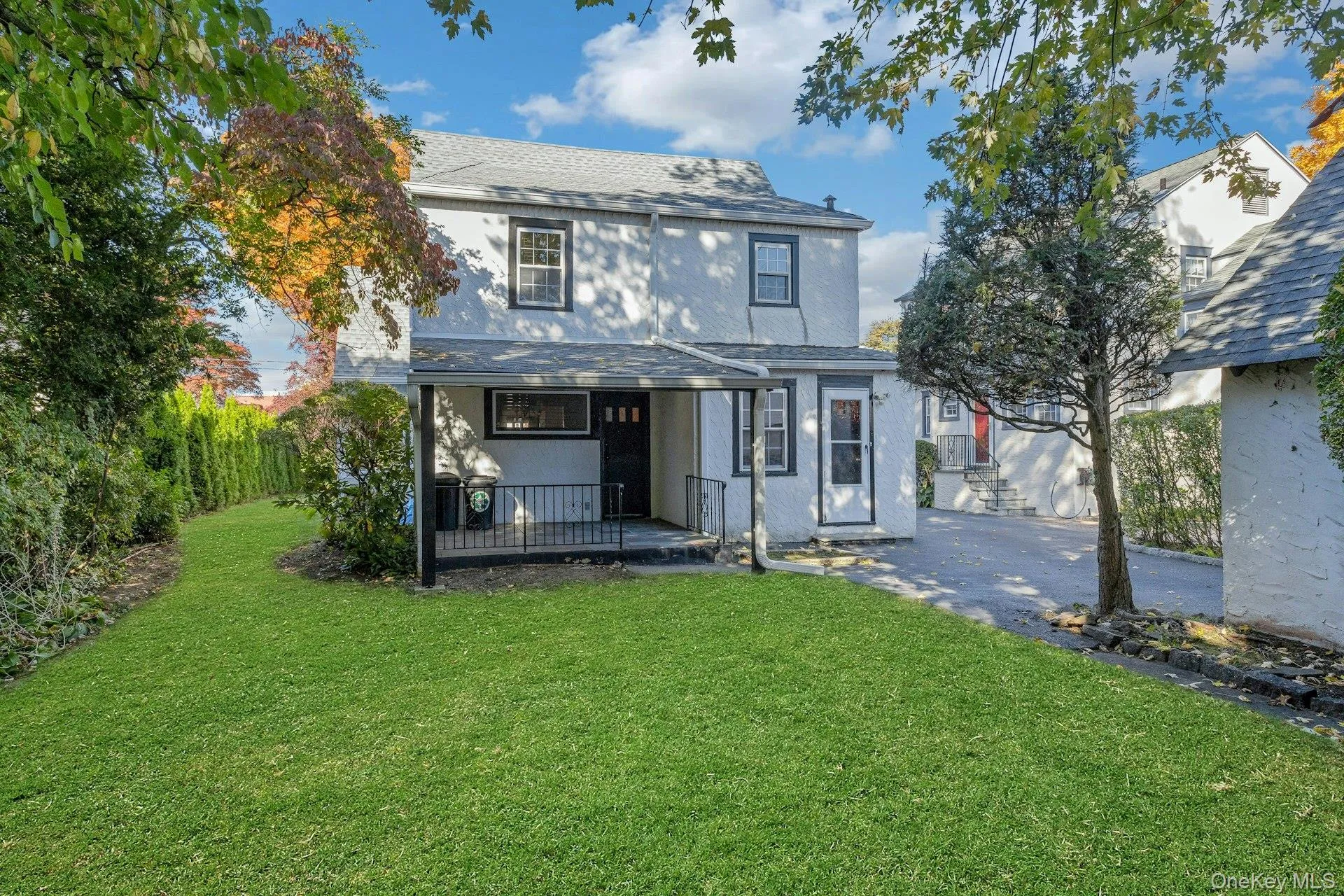 View of front of property with a front lawn, a shingled roof, a porch, and stucco siding View of front of property with a front lawn, a shingled roof, a porch, and stucco siding