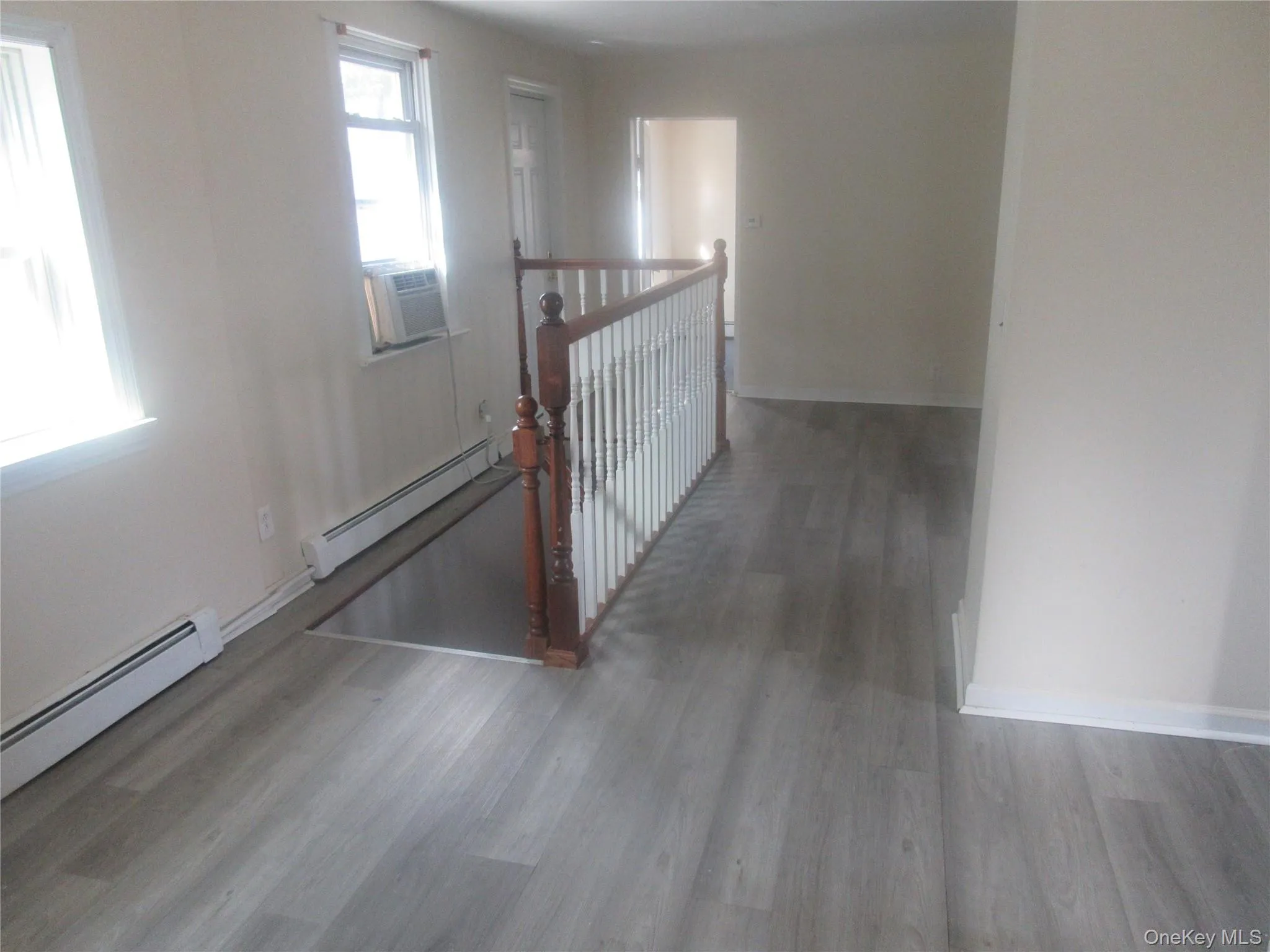 Hallway featuring baseboard heating, wood finished floors, and cooling unit Hallway featuring baseboard heating, wood finished floors, and cooling unit