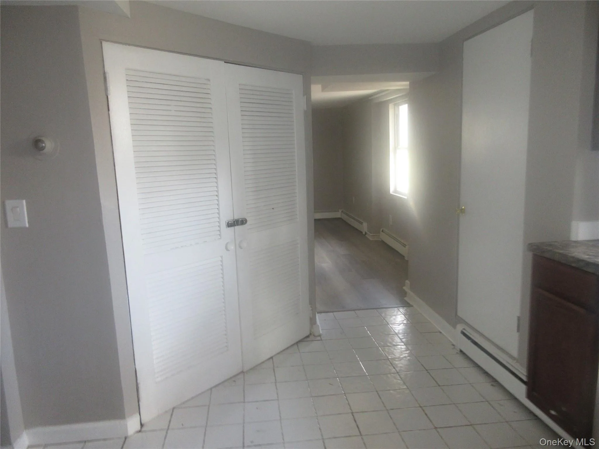 Hall with a baseboard heating unit and light tile patterned flooring Hall with a baseboard heating unit and light tile patterned flooring