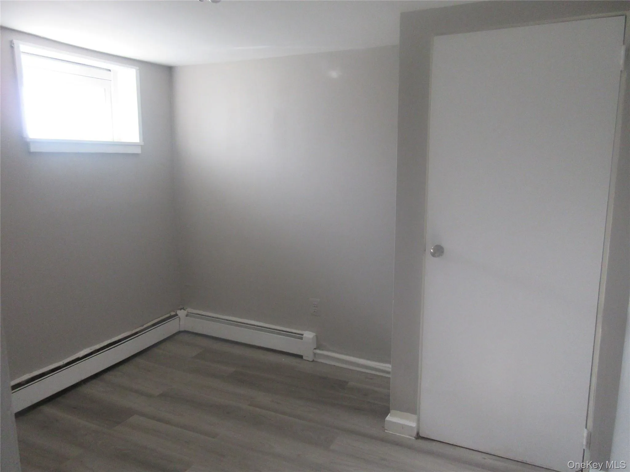 Spare room featuring light wood-style flooring and a baseboard heating unit Spare room featuring light wood-style flooring and a baseboard heating unit