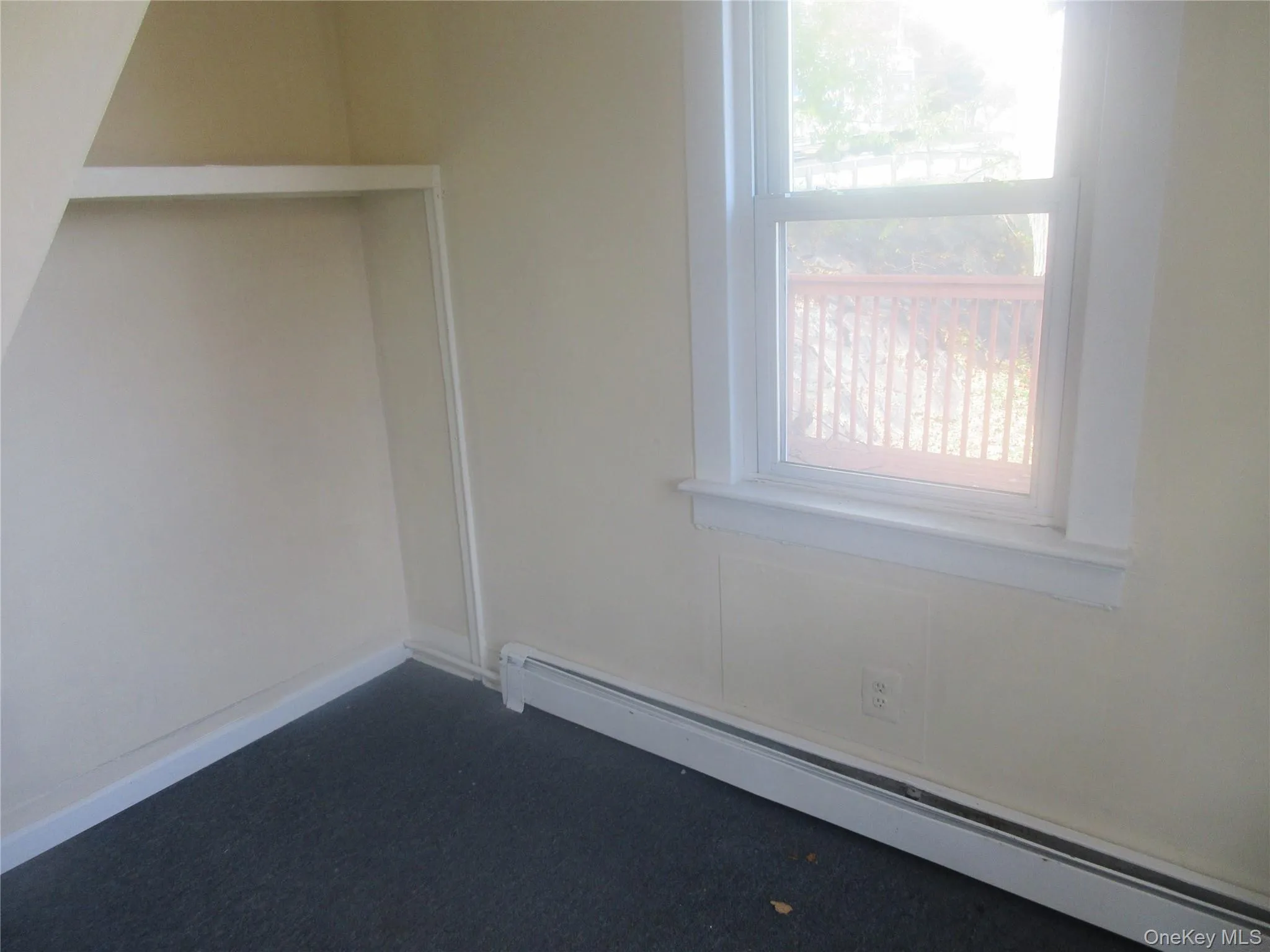 Empty room with a baseboard heating unit and dark carpet Empty room with a baseboard heating unit and dark carpet