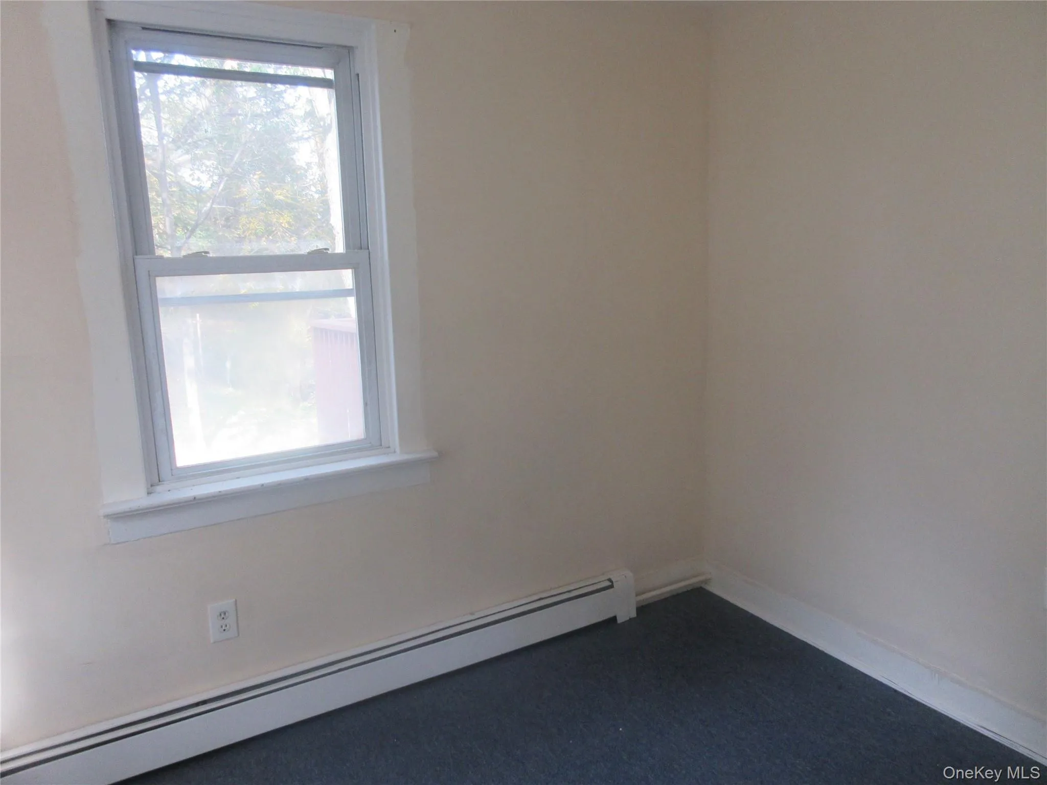 Empty room with baseboard heating and dark carpet Empty room with baseboard heating and dark carpet