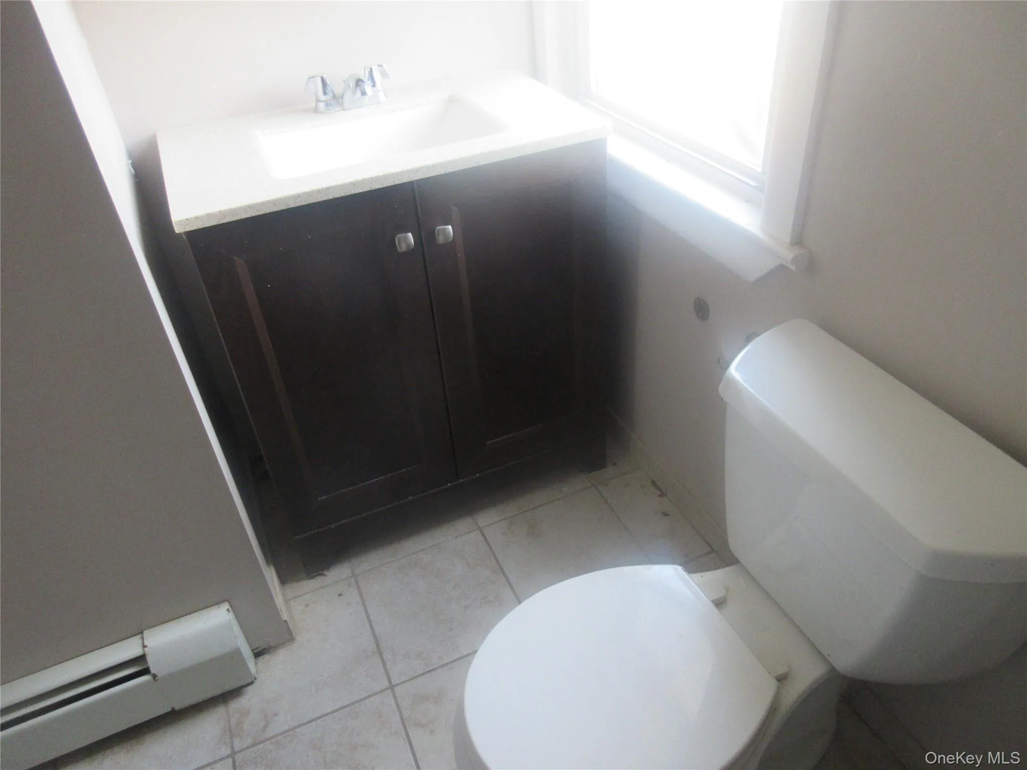 Bathroom with a baseboard radiator, vanity, and light tile patterned floors Bathroom with a baseboard radiator, vanity, and light tile patterned floors